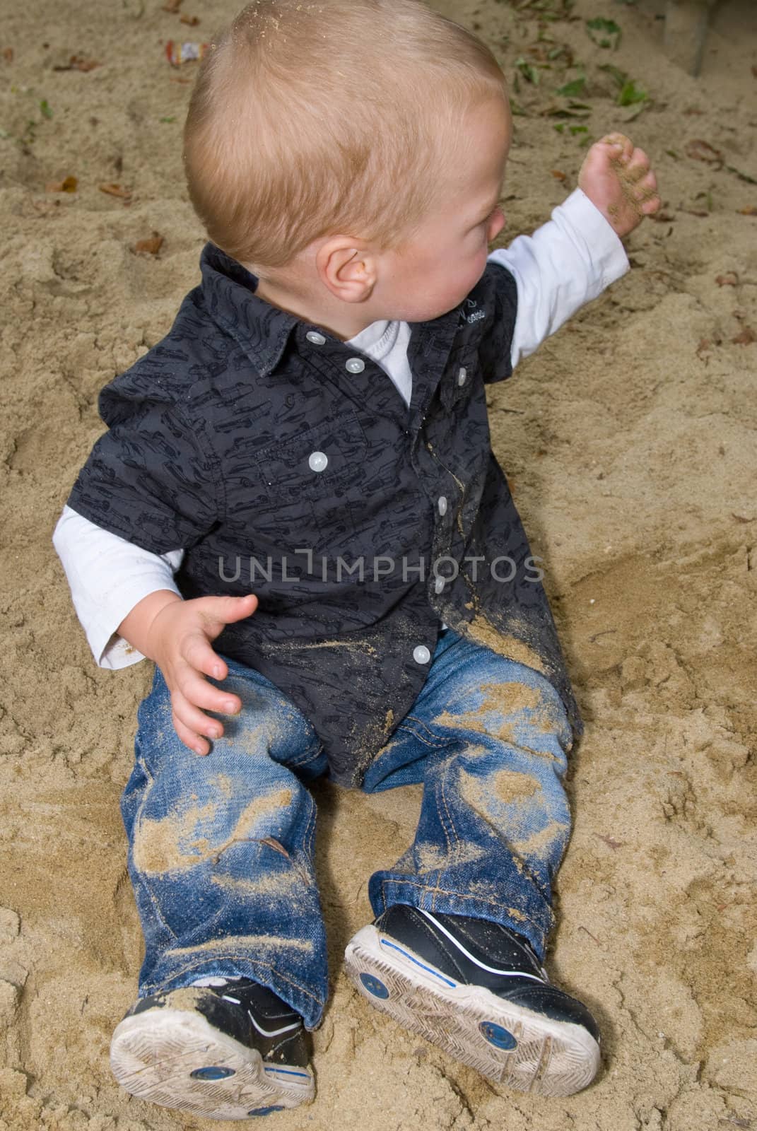 a little boy distributing the sand in the sandbox 