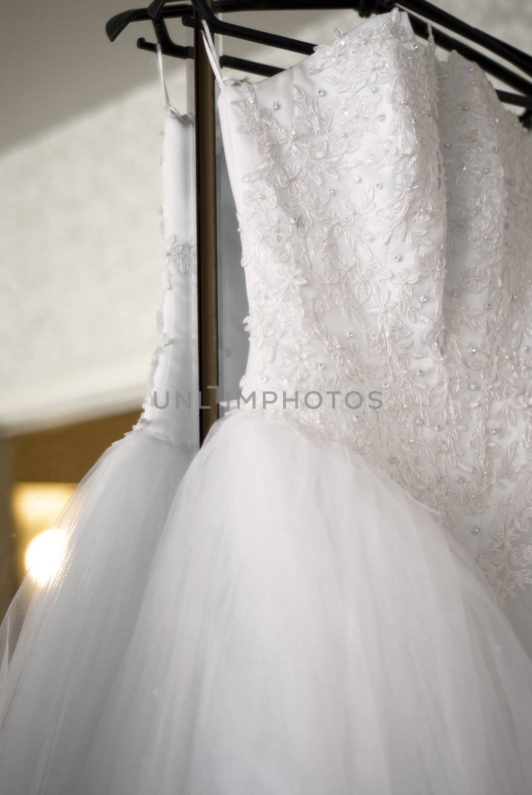 White wedding dress hang on wardrobe door and small lantern shine like a sun.