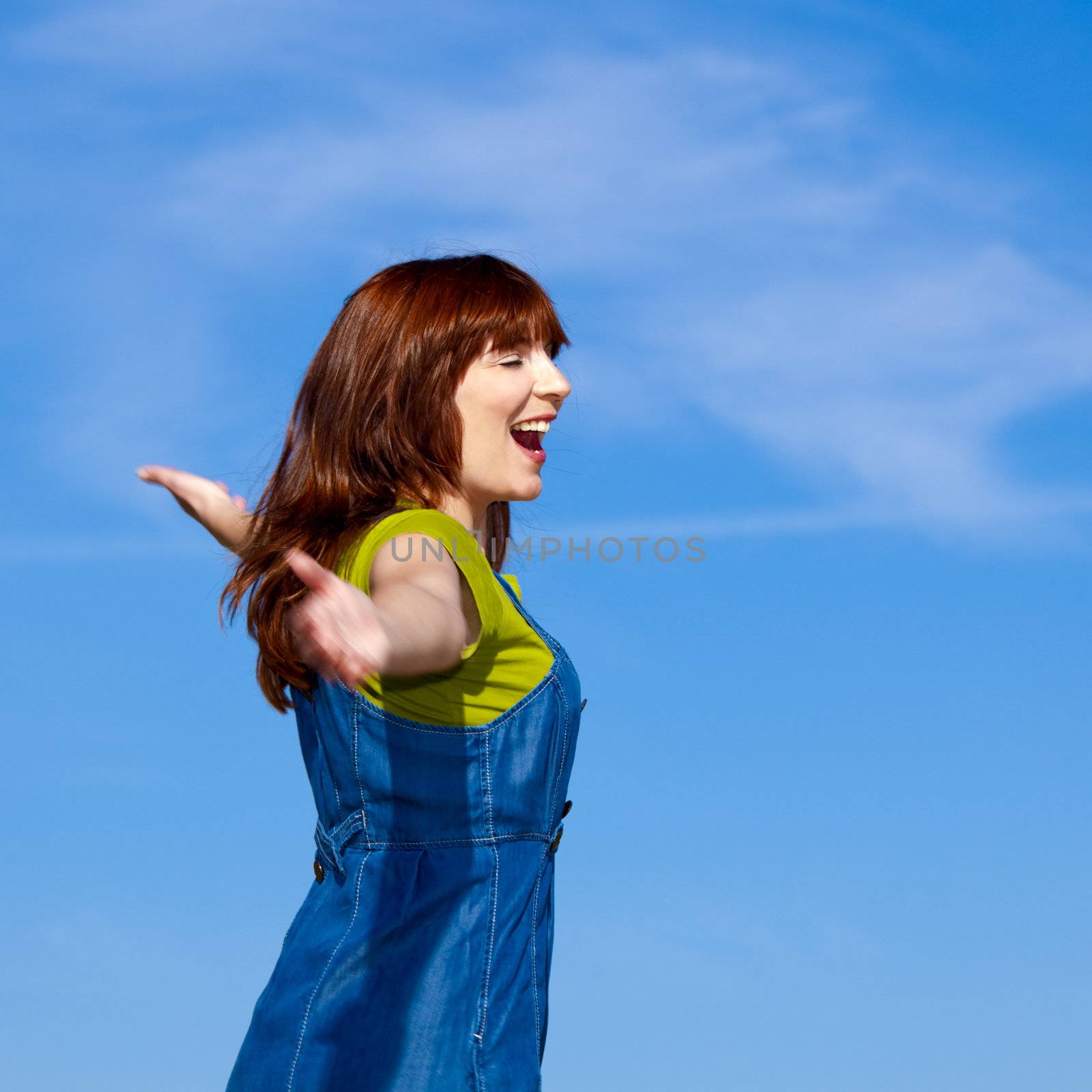 Portrait of a beautiful woman over a blue sky with arms open