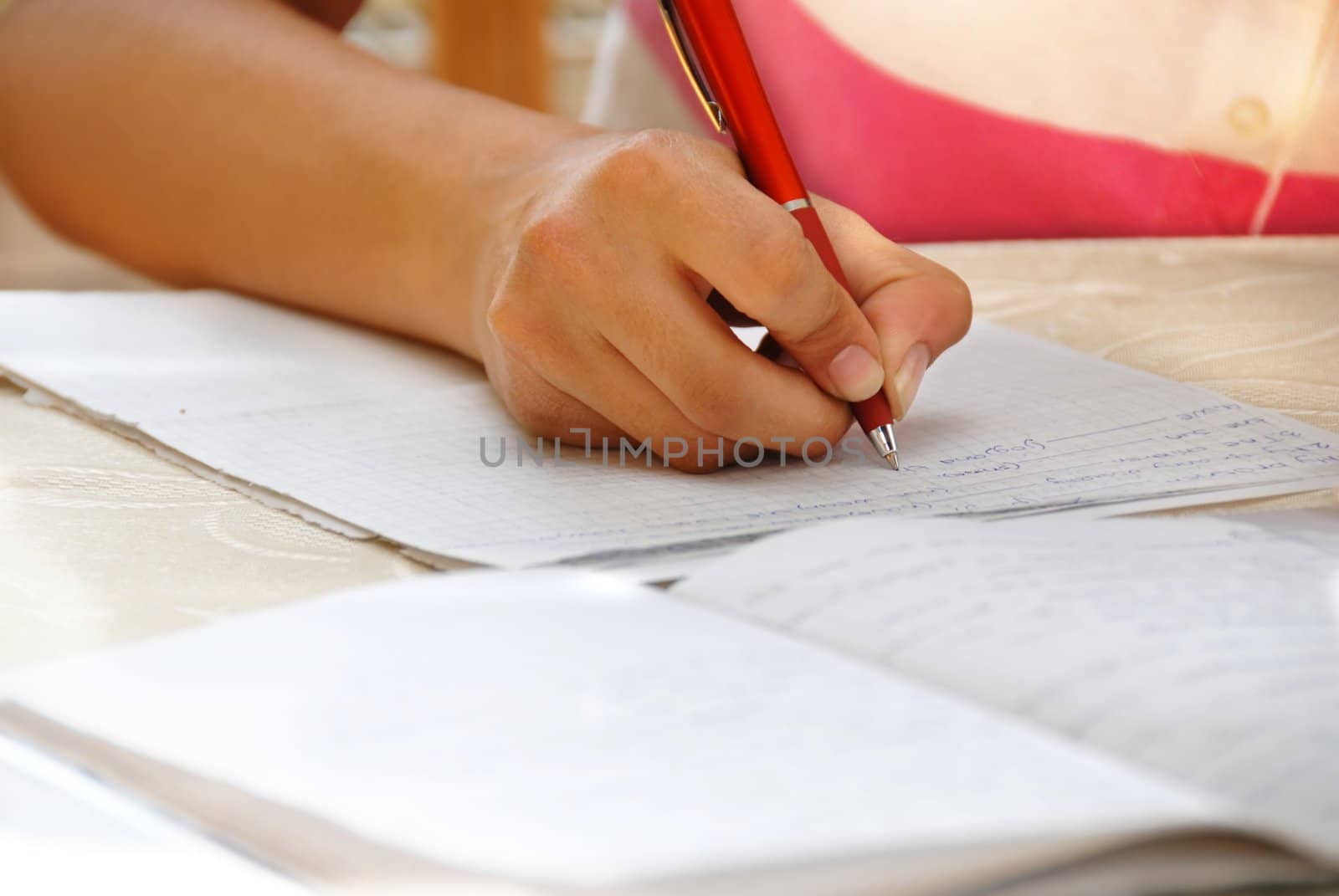 schoolgirl with pen writing down in notebook homework