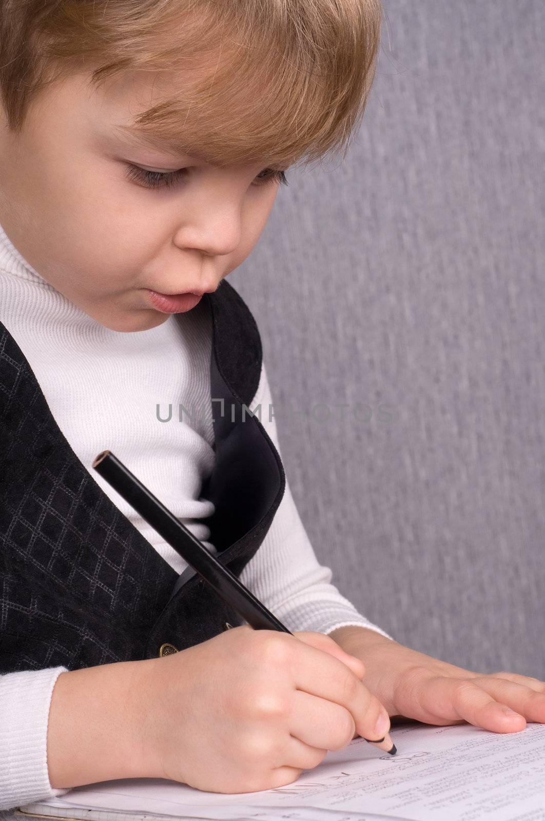 Six years boy sitting and writing in notebook