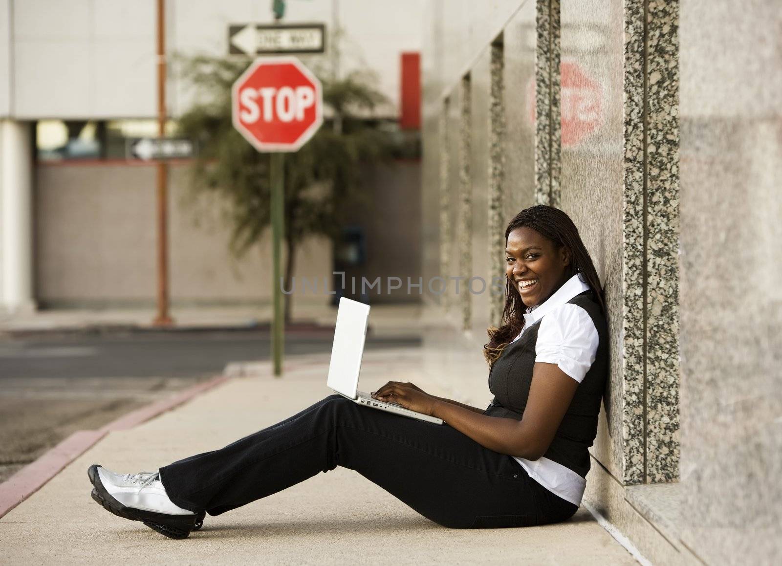 Pretty African American woman on sidealk with laptop computer