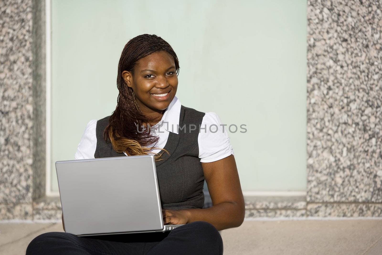 Pretty African American woman on sidealk with laptop computer
