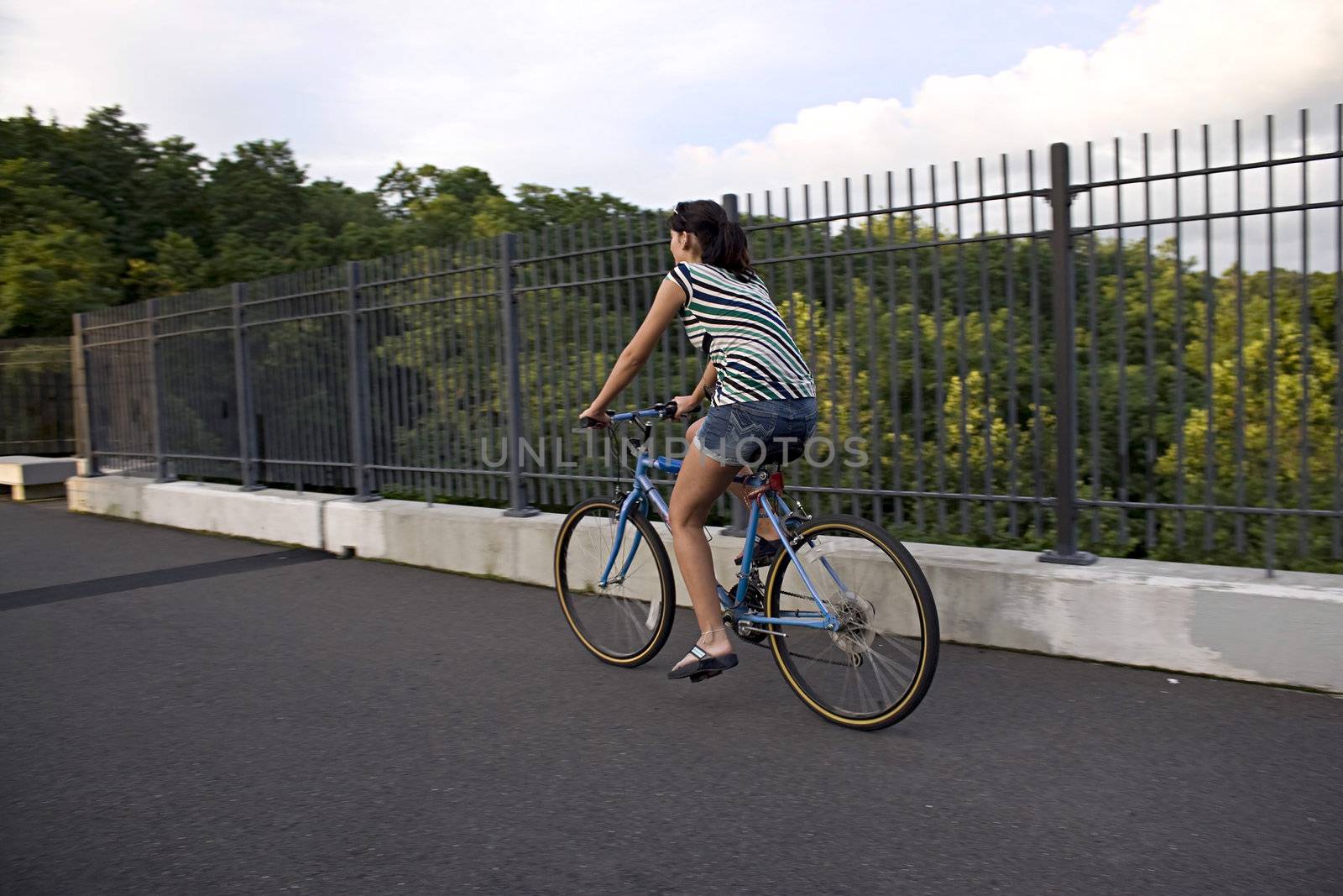 A young woman riding a bicycle across the bridge.