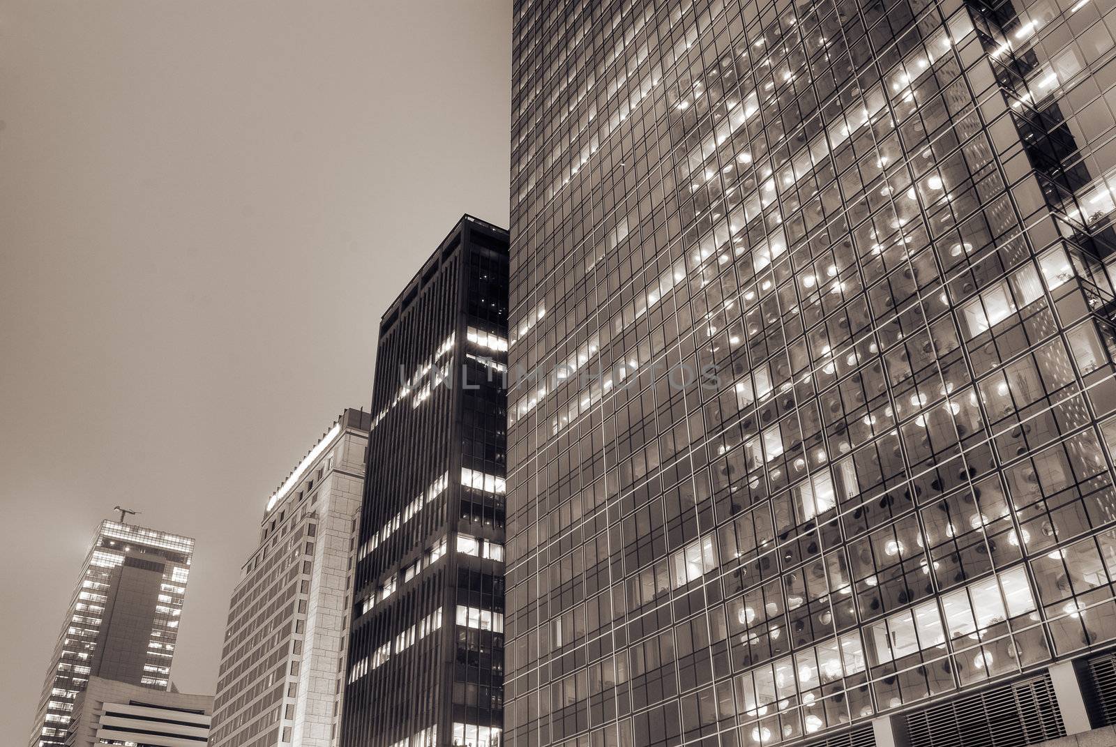 Cityscape of modern building exterior with glass windows in night.