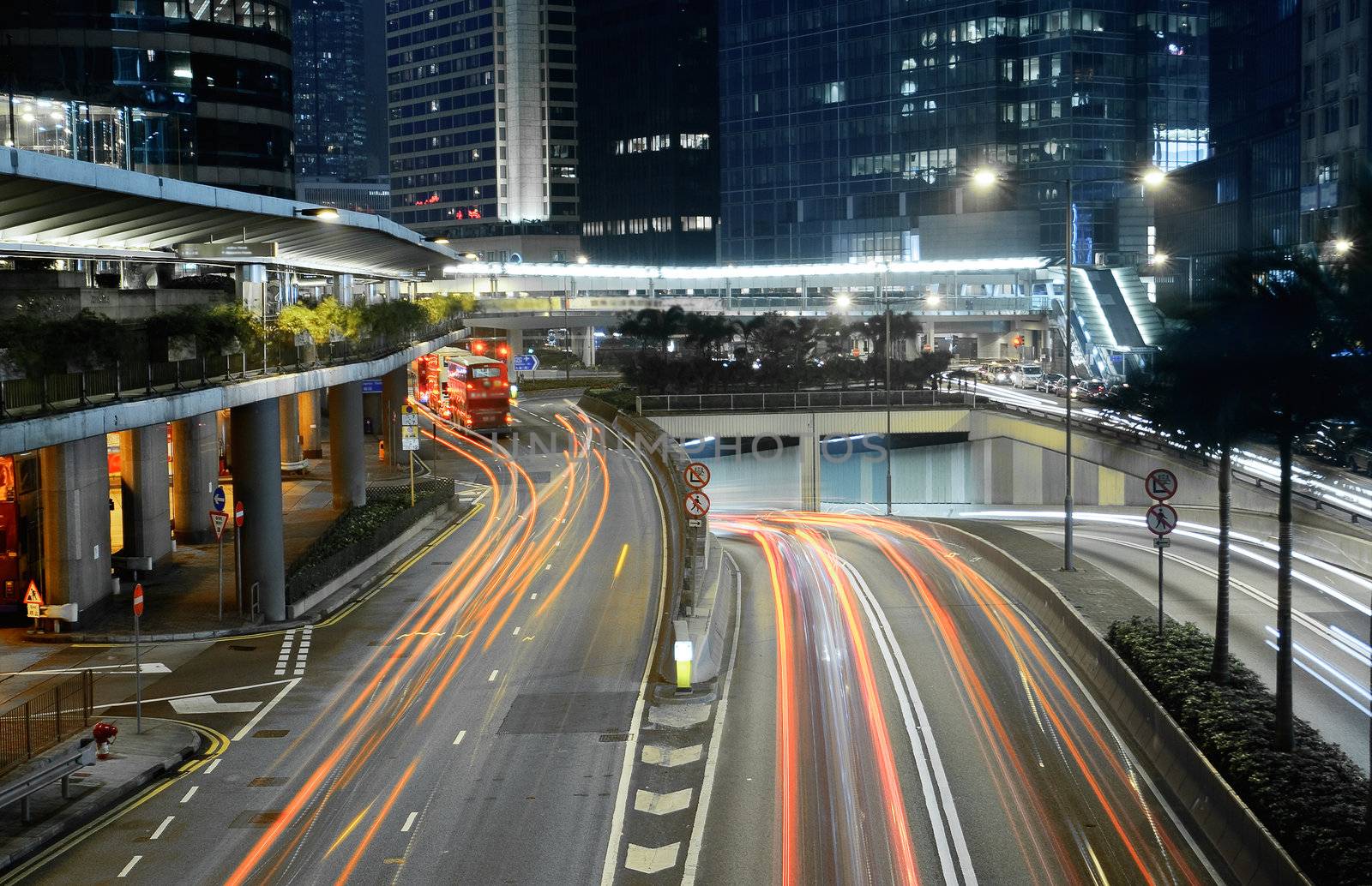 Traffic in city with cars motion blurred light and office building in night.