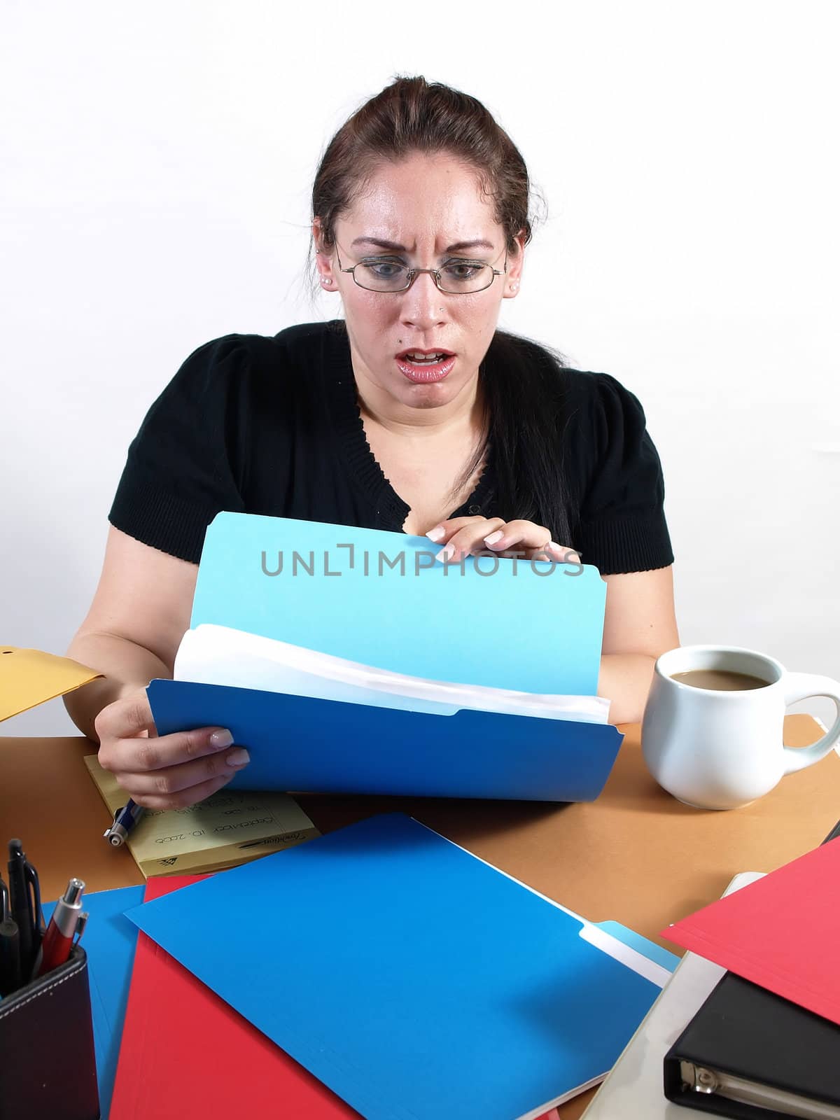 A female office worker checks a file with a worried look on her face.