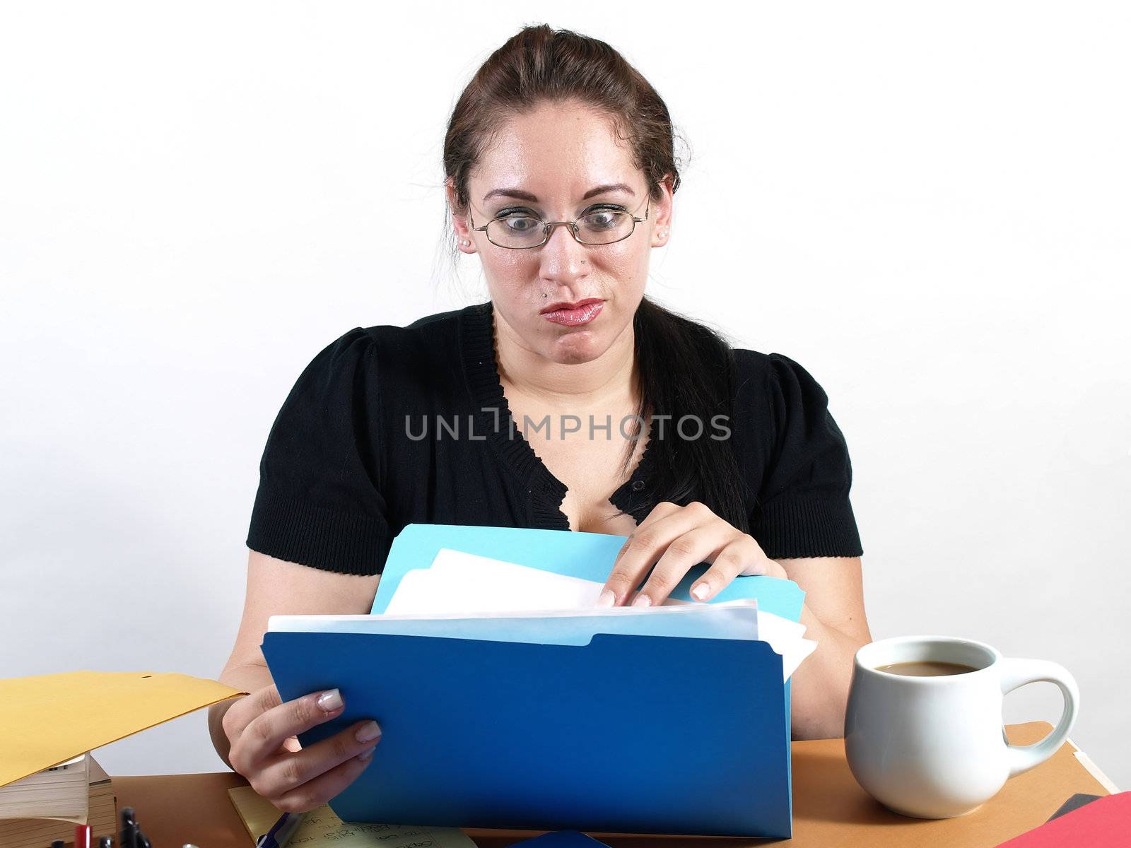 A female office worker checks a file with a worried look on her face.