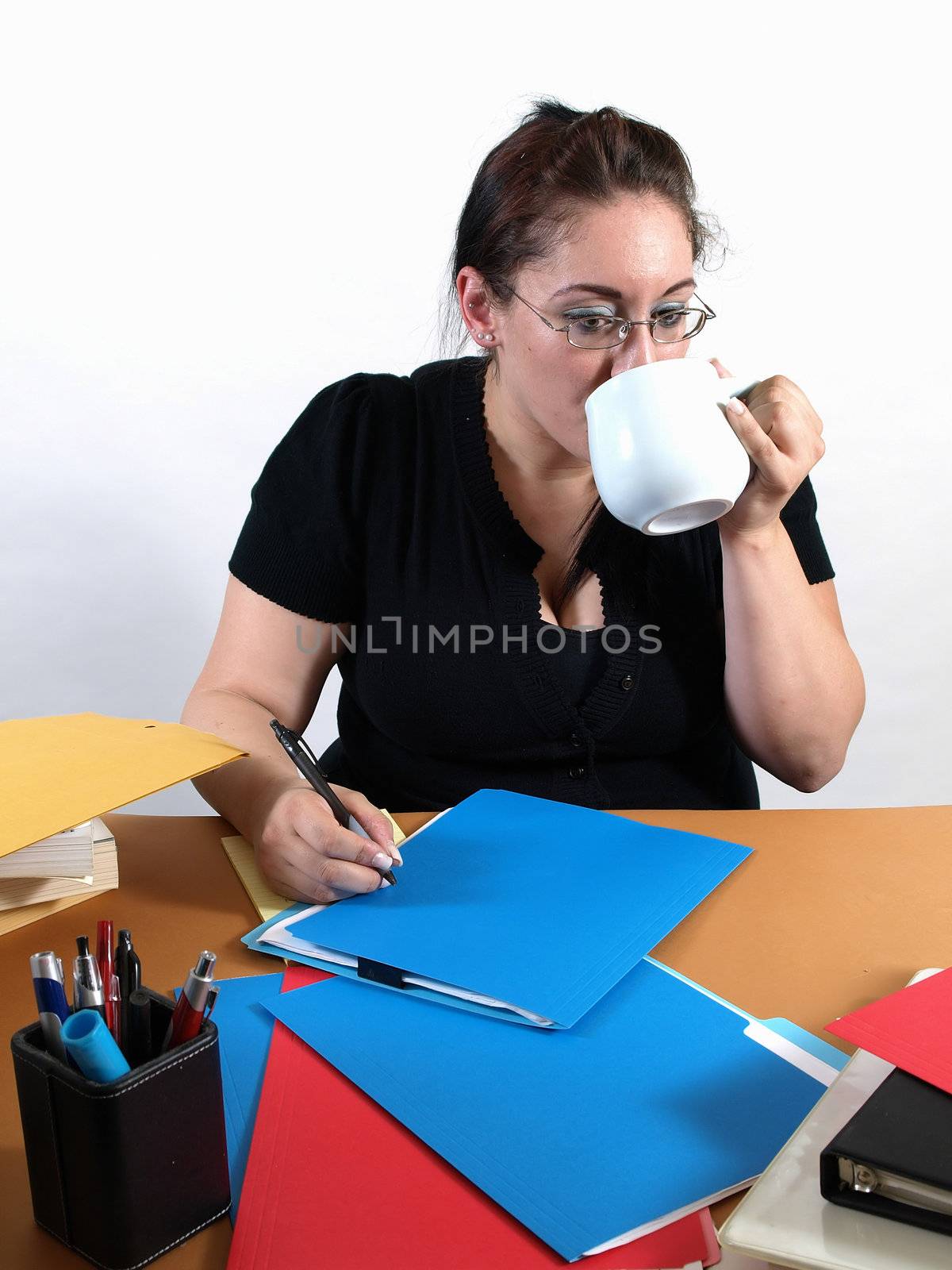 A female office worker takes a quick break with a sip of coffee.