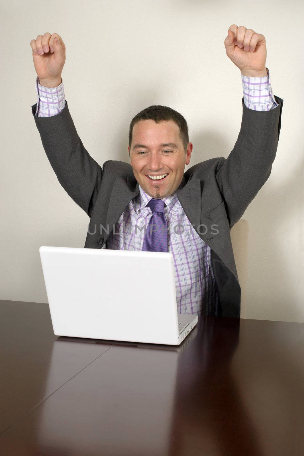 Happy businessman in his thirties looks at his success on his laptop.
