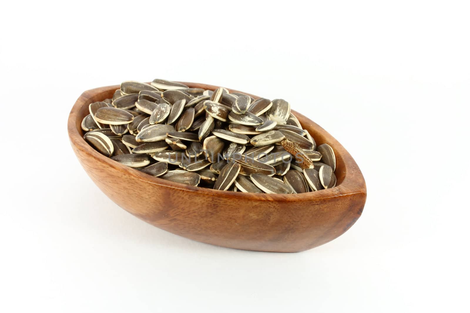 Wood bowl full of  unshelled sunflower seeds, isolated on white