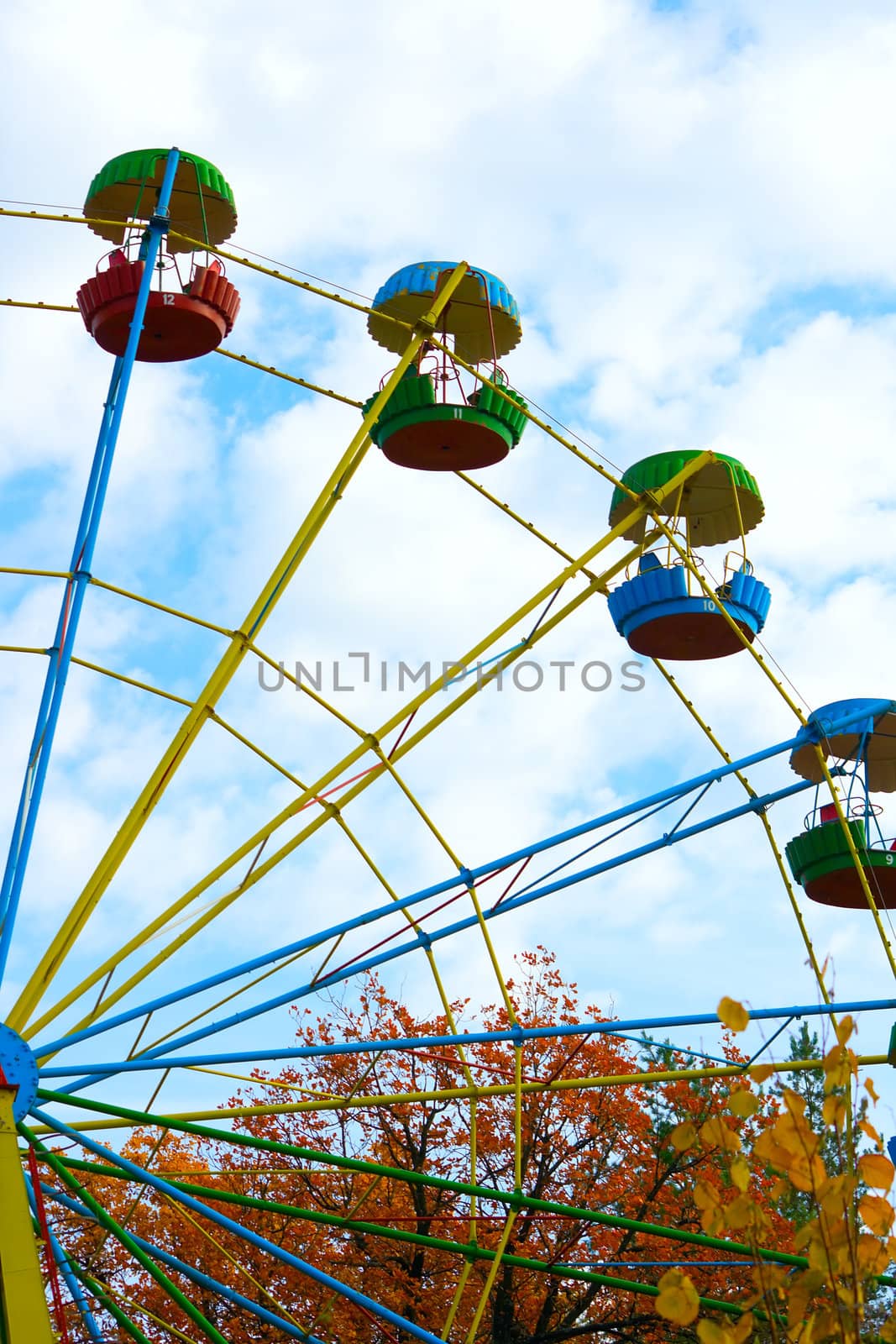 Old big wheel in autumn park against the blue cloudy sky