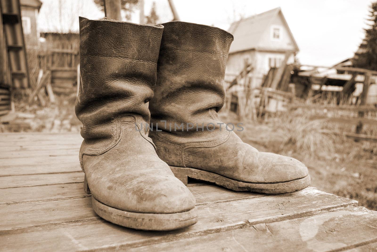 old muddy farmers boots on background wooden wall.tone sepia