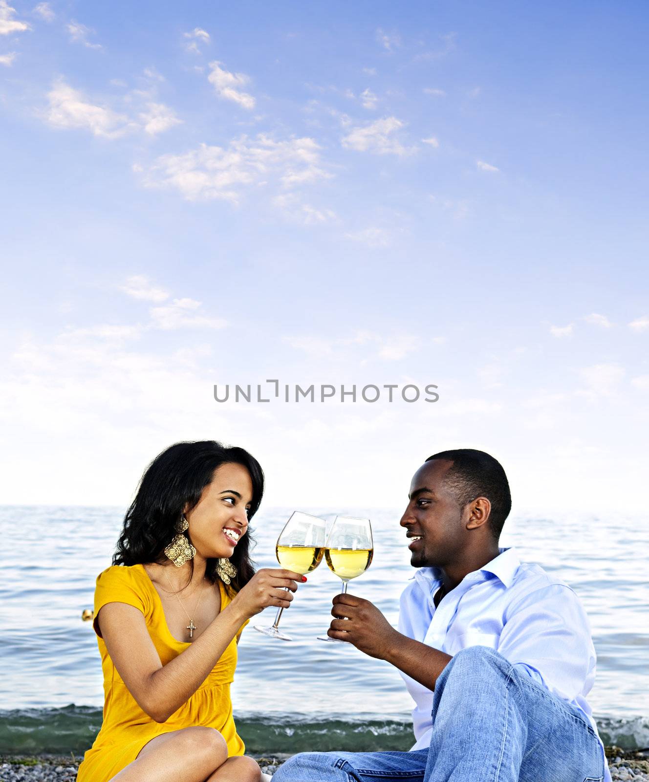 Young romantic couple celebrating with wine at the beach with copyspace