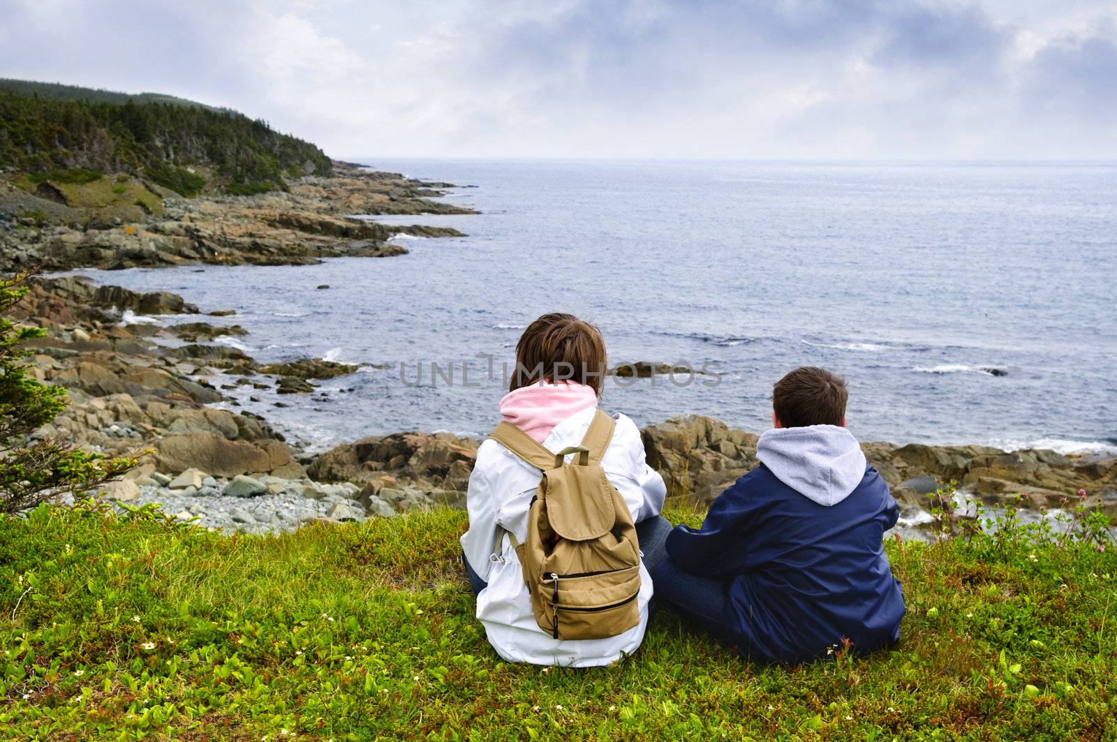 Children sitting at Atlantic coast in Newfoundland by elenathewise