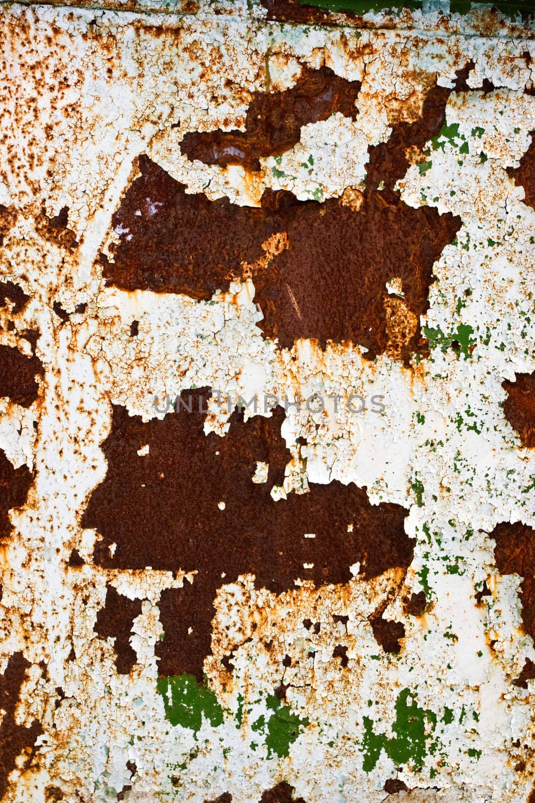 White and green peeling paint on rusty steel wall