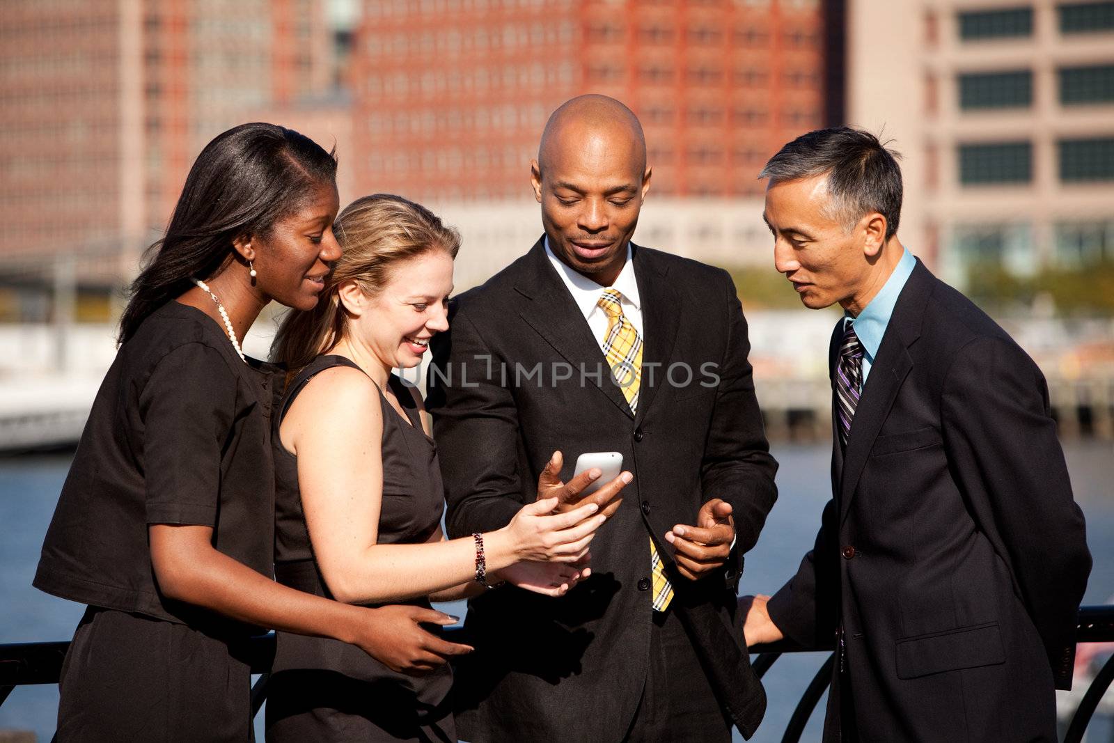 A group of business people crowded around a cell phone