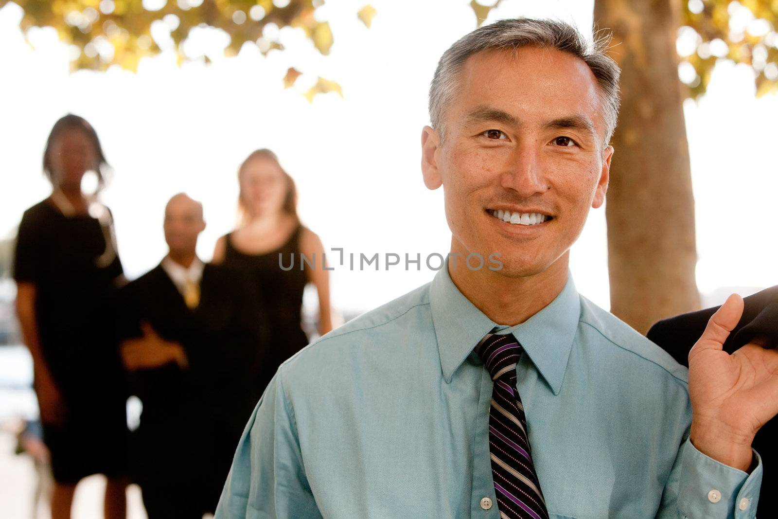 An asian looking business man with colleagues in the background