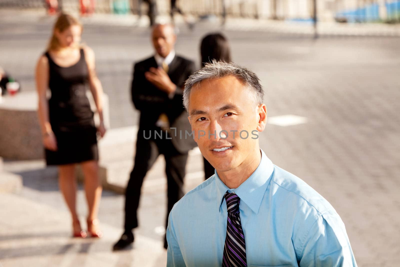 A casual business man with colleagues in the background - outdoor portrait