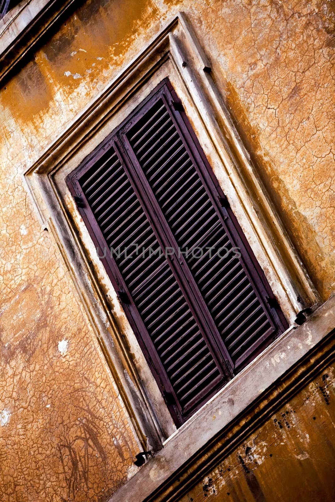 Window on old orange wall in Rome, Italy