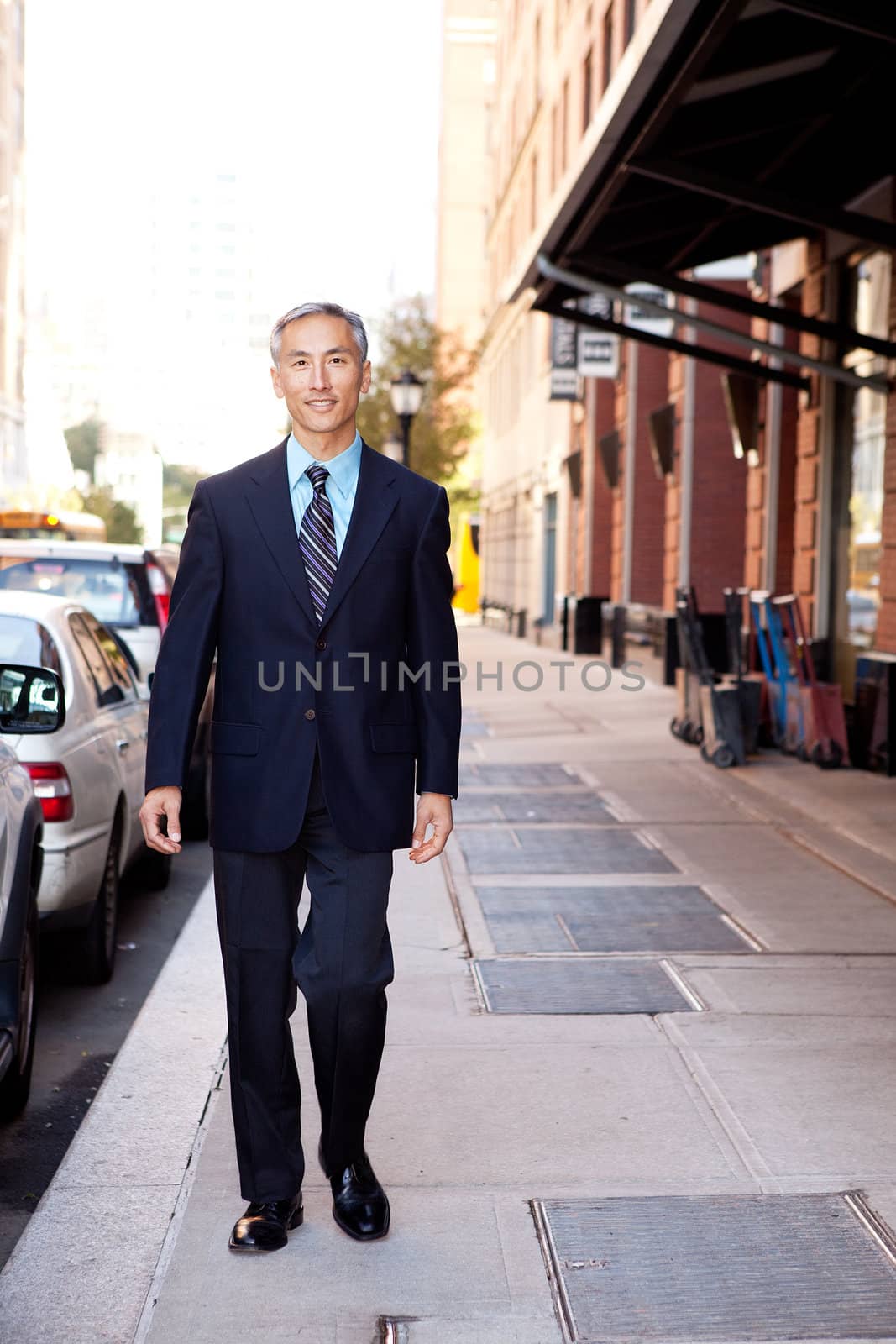 An asian looking business man walking in a street