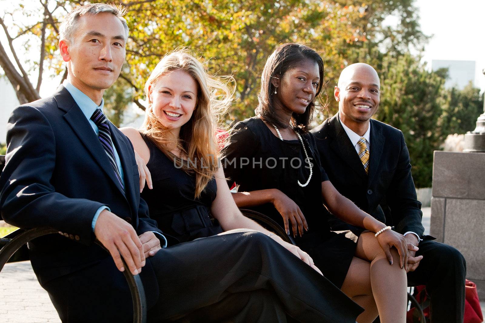 A multicultural business team on a bench in a park