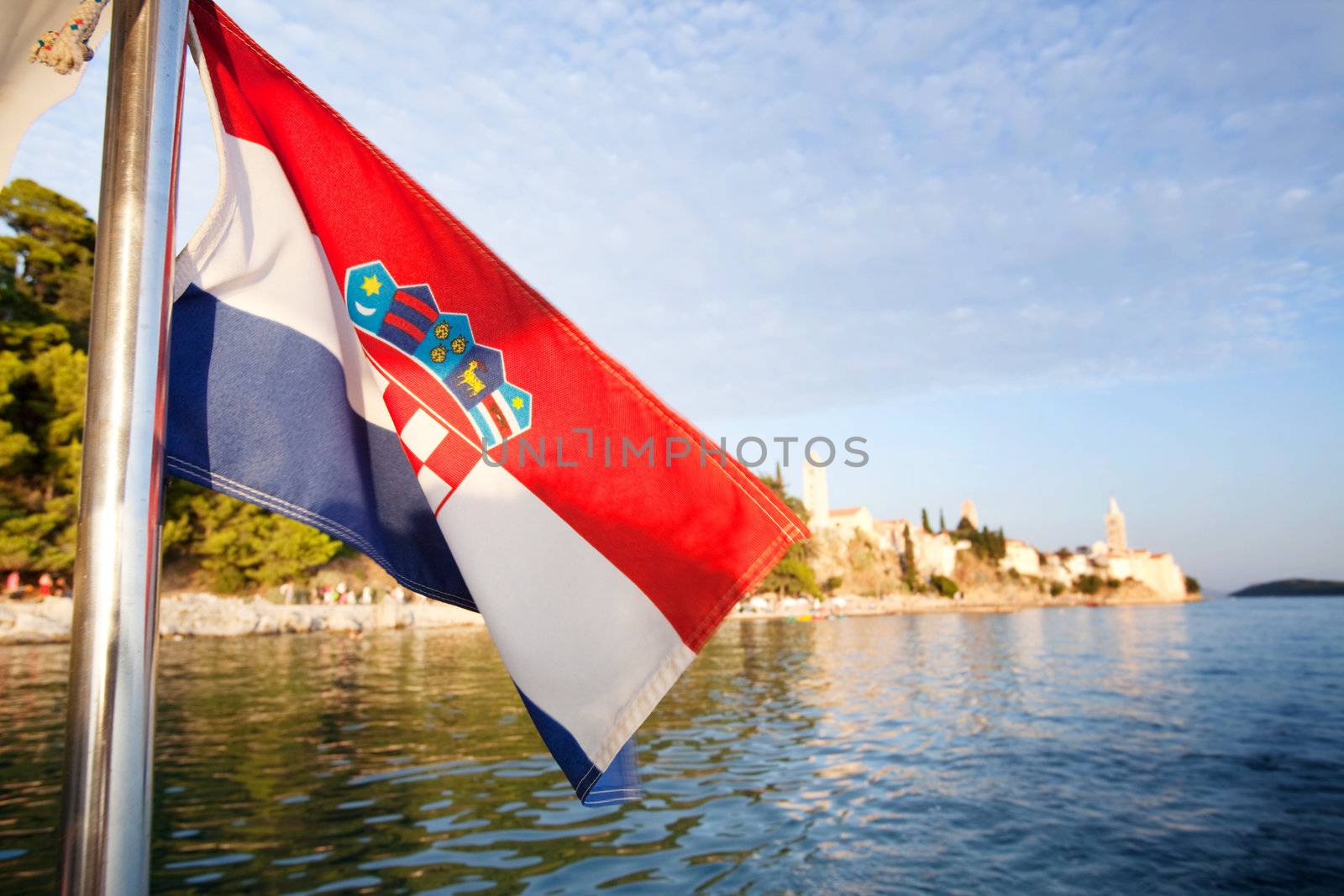 A croatian flag in front of a landscape of the island of Rab