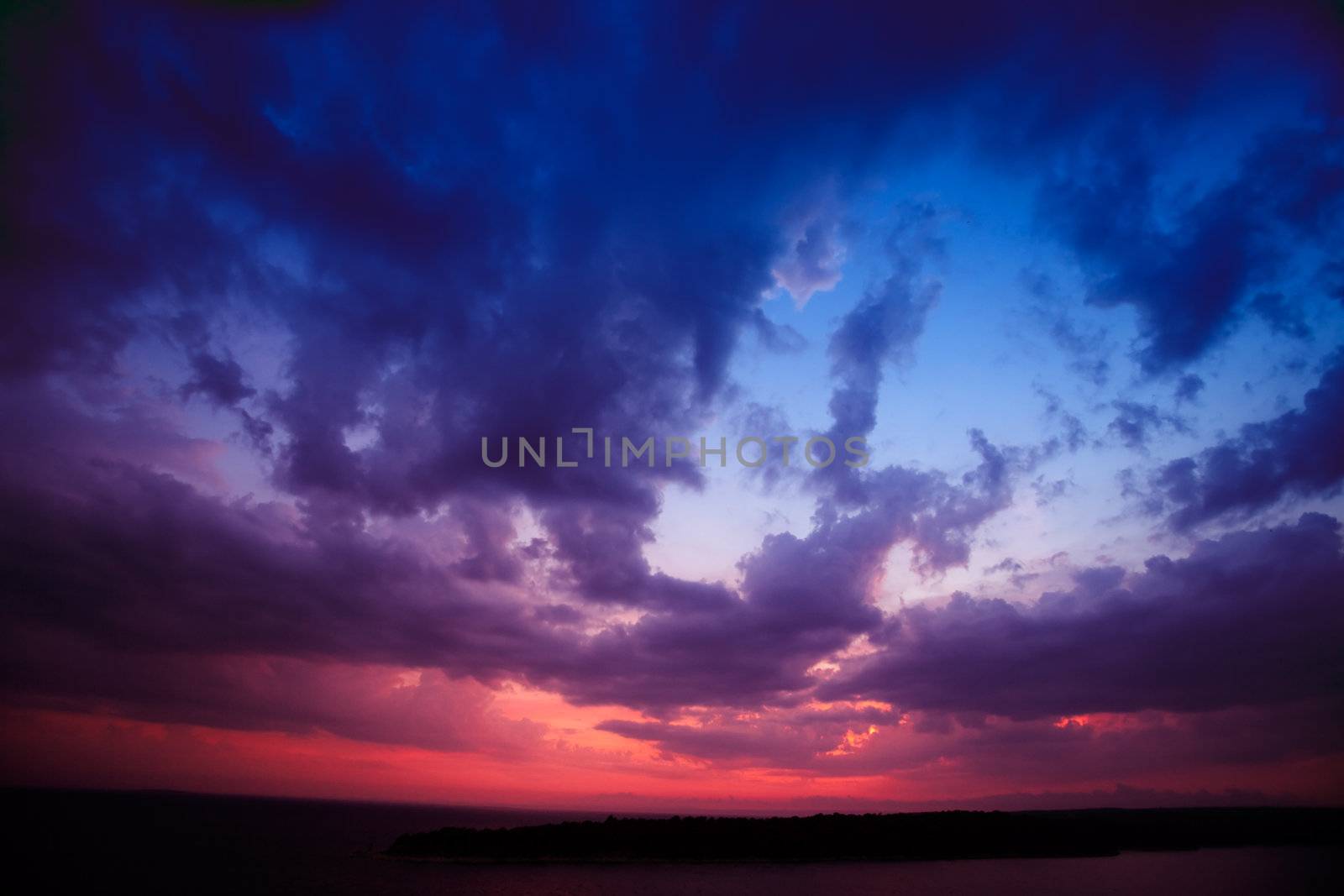 A dark landscape at sunset over the ocean