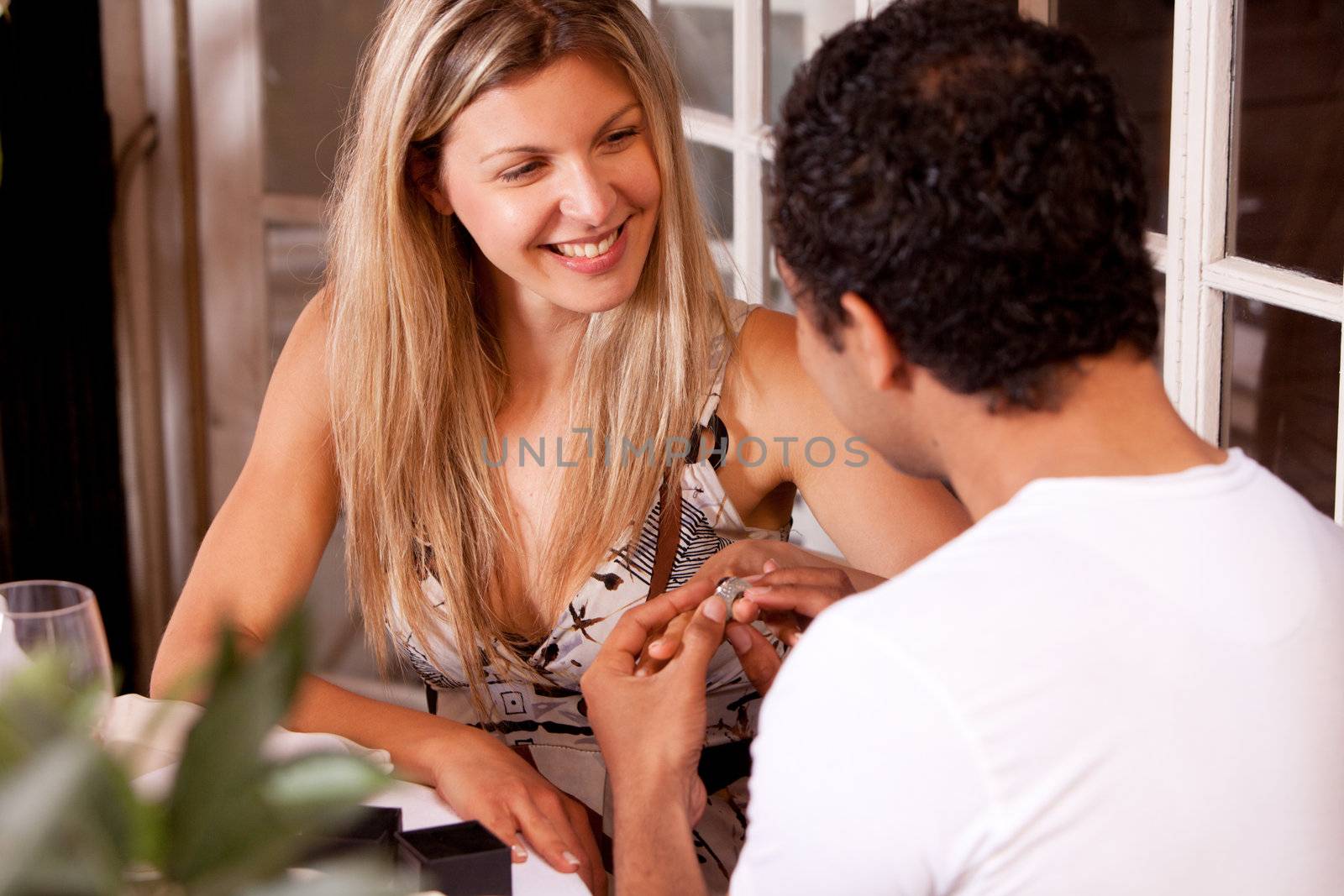 A man giving a ring as a gift to a female in an outdoor cafe