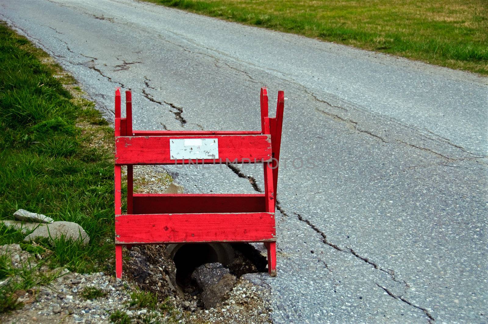 A red wooden roadblock on a bumpy road