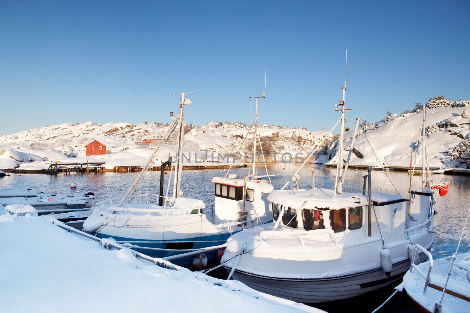 A dock in southern Norway with boats covered in snow