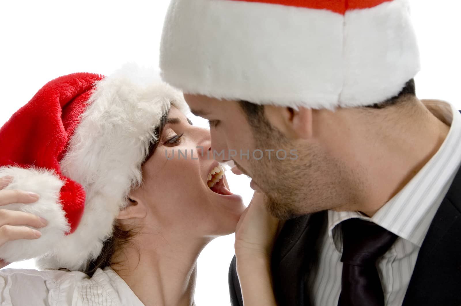 couple kissing and wearing santa cap by imagerymajestic