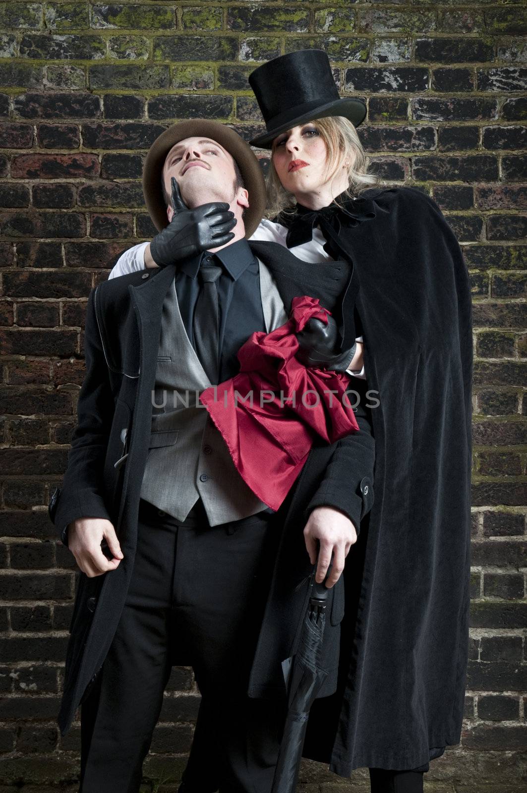 Fashion shot of woman  dressed as Jack the Ripper stealing man's handkerchief.