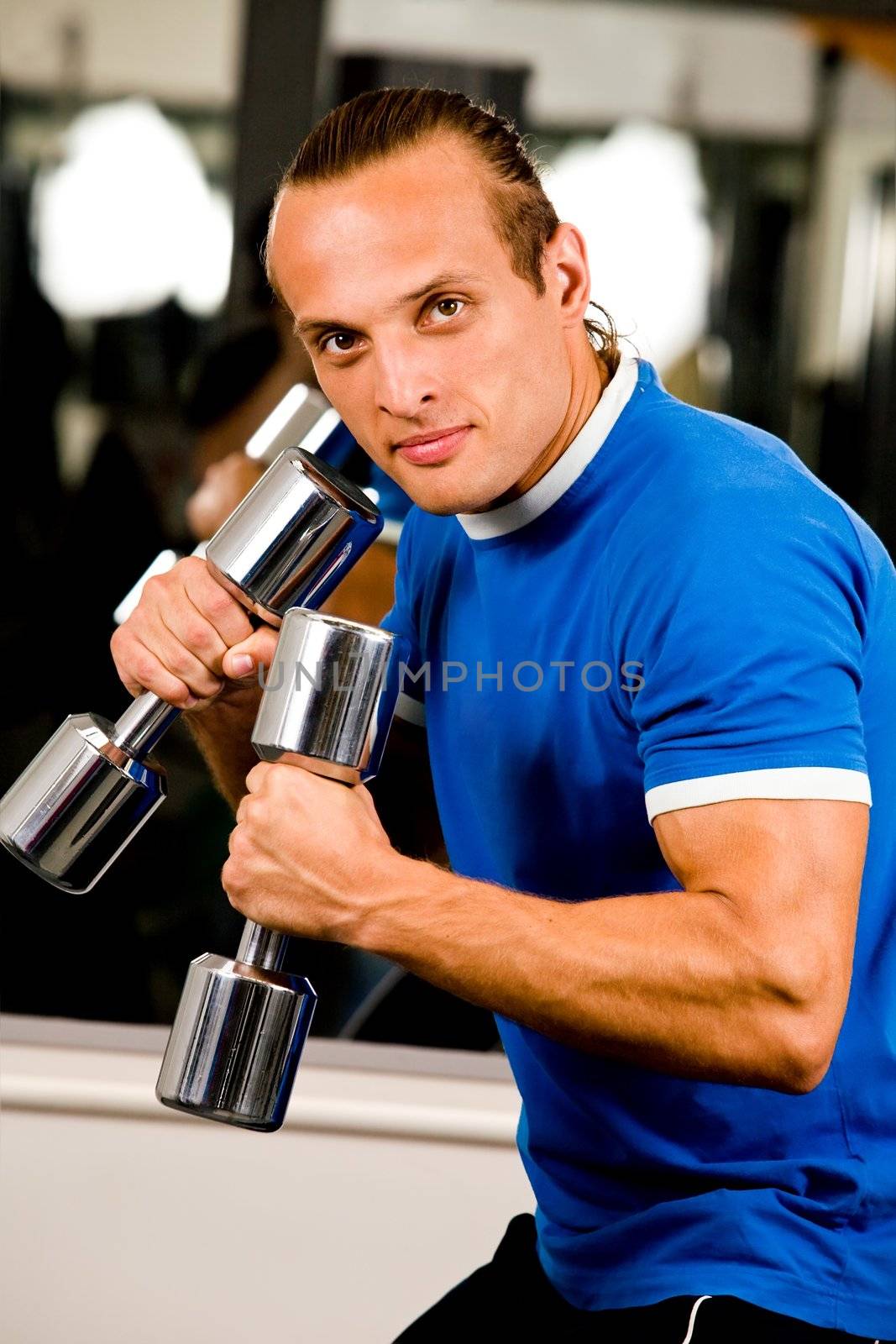 Strong man in health club curling a dumbbell