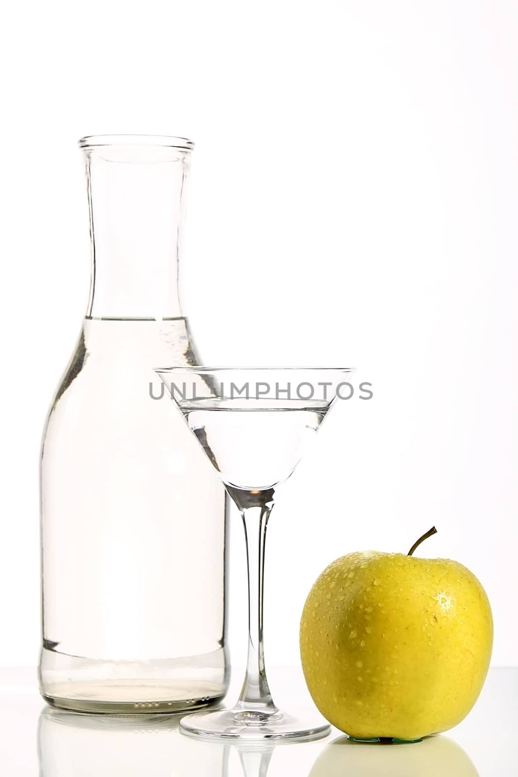 Bottle with transparent water, a glass and apples on a white background