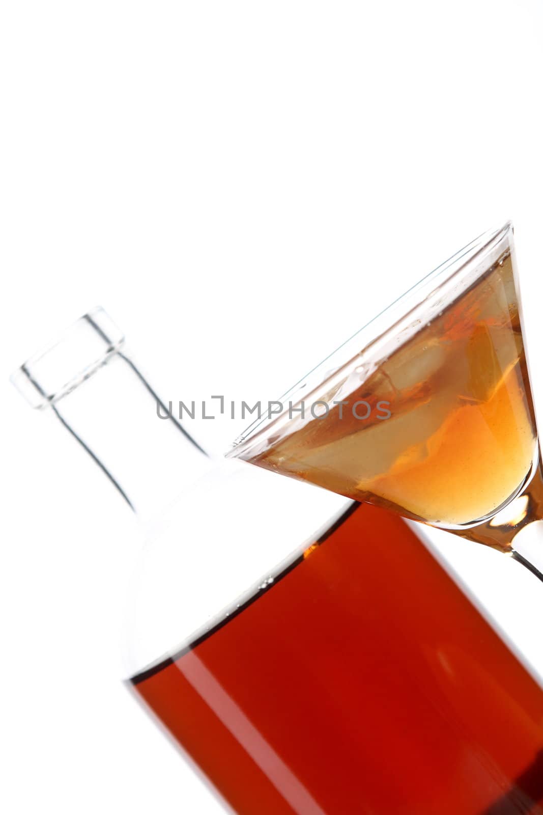 Bottle with an alcoholic drink, a glass and an orange on a white background