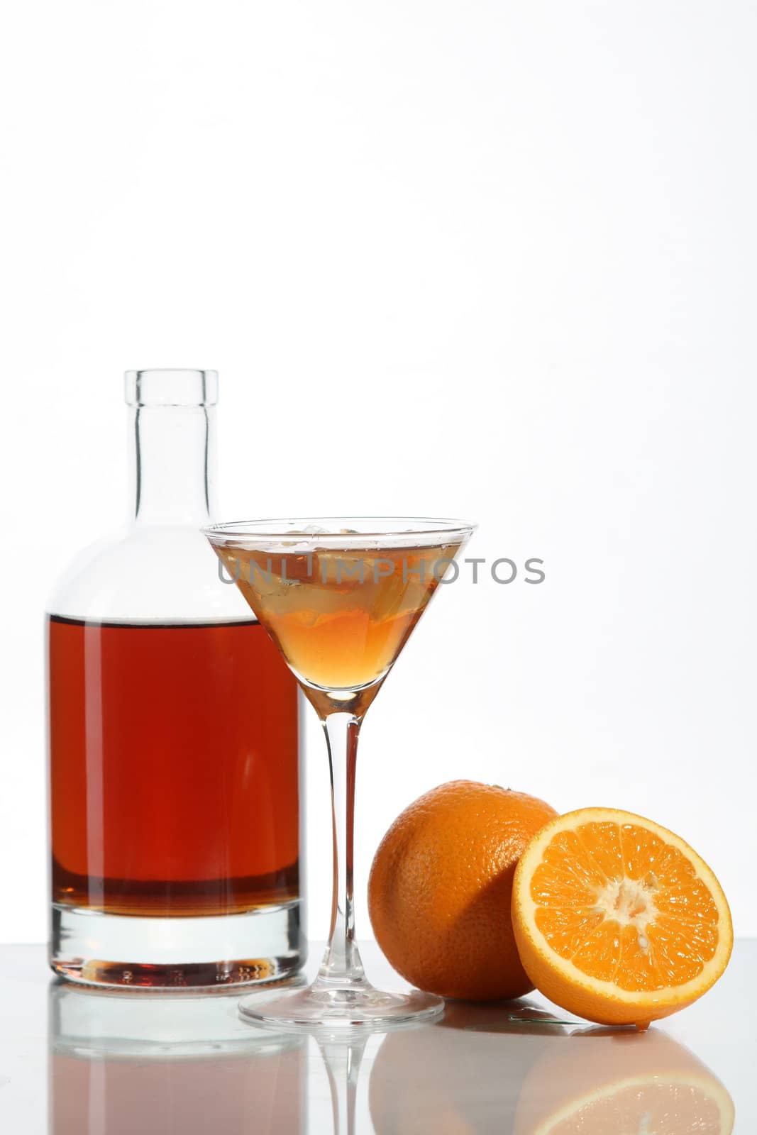 Bottle with an alcoholic drink, a glass and an orange on a white background