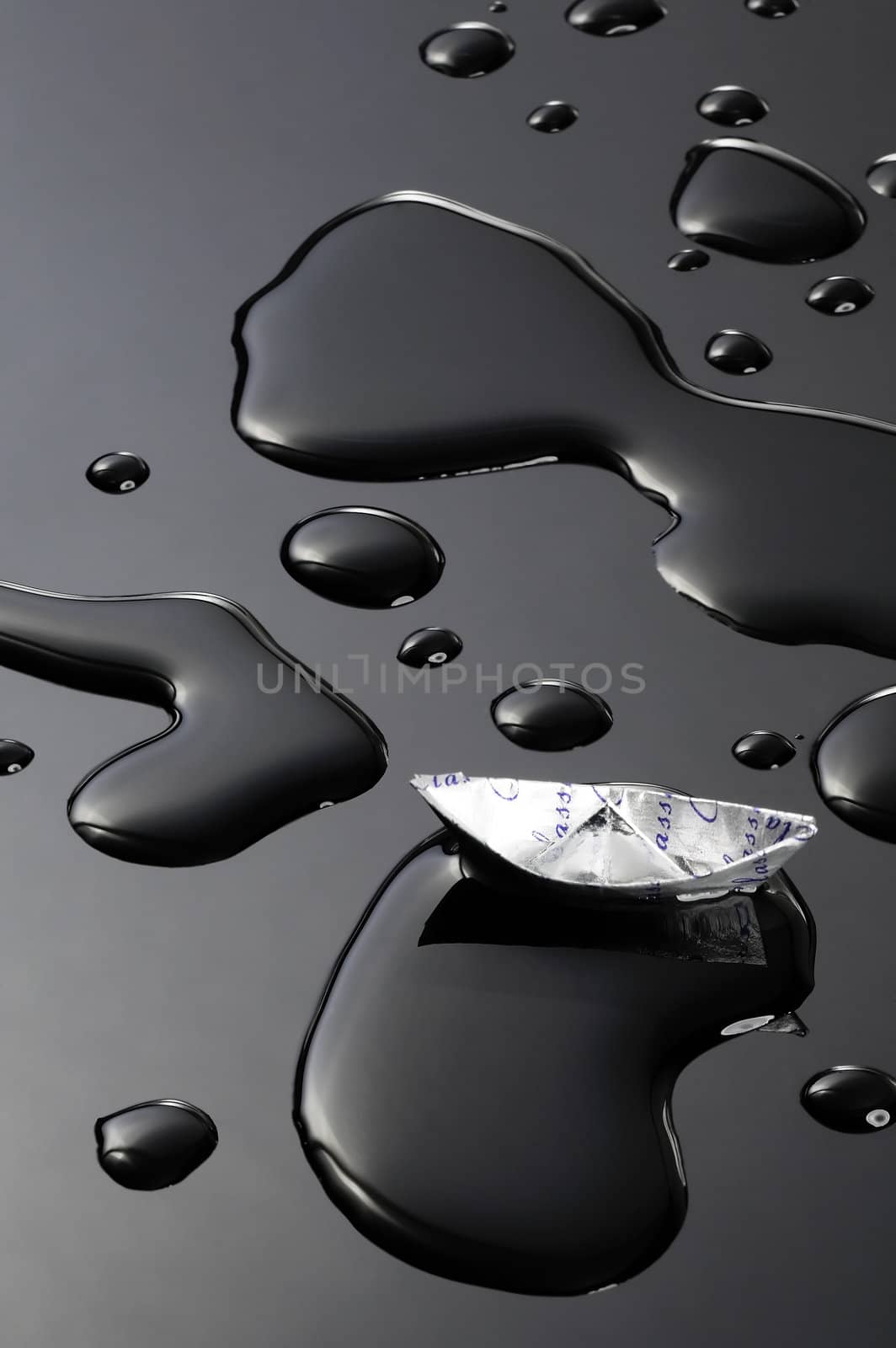 paper boat floating on water drops over black background