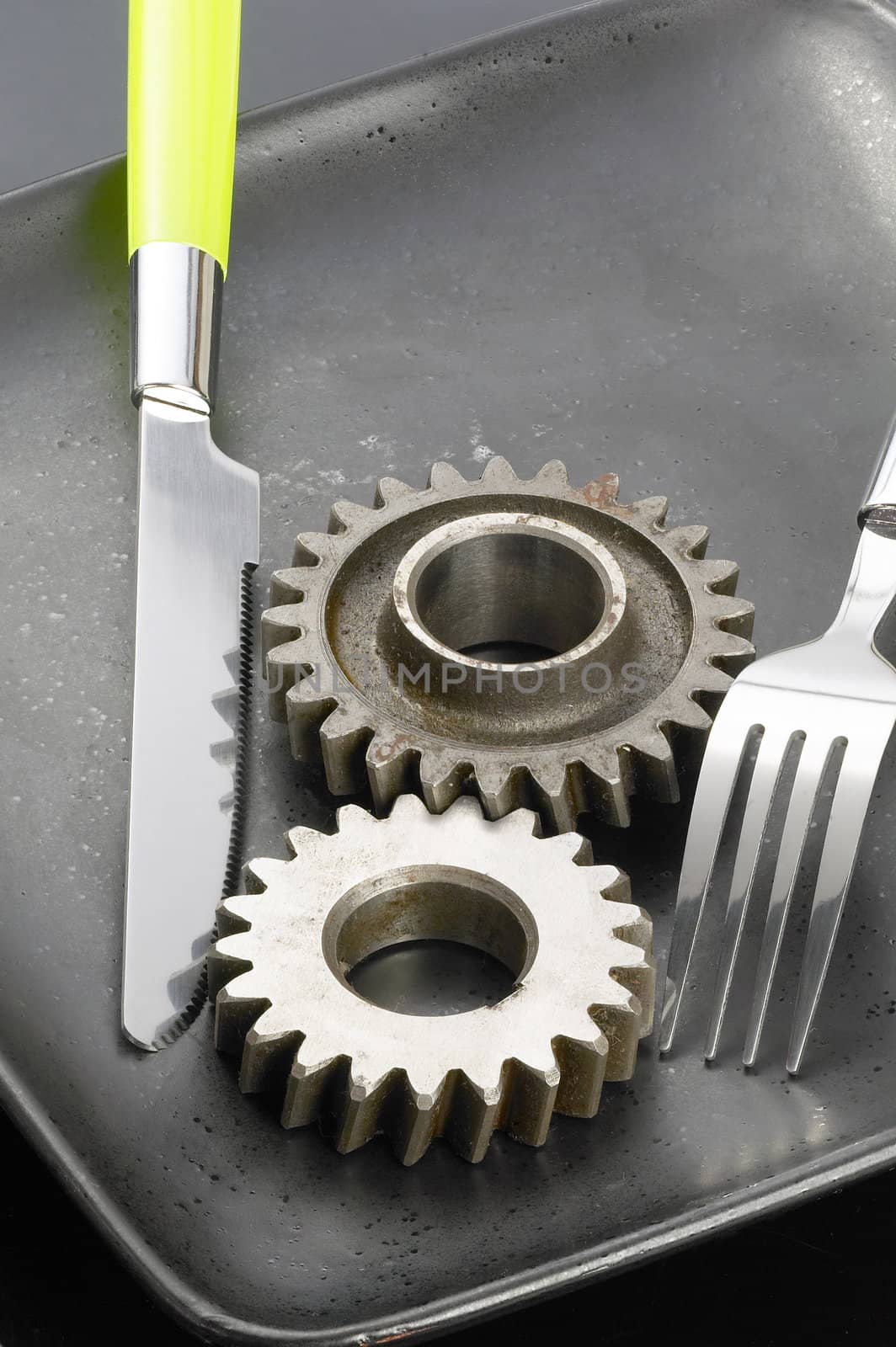 gearwheels on a black plate with knife and fork