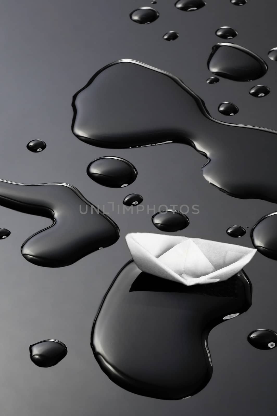 paper boat floating on water drops over black background