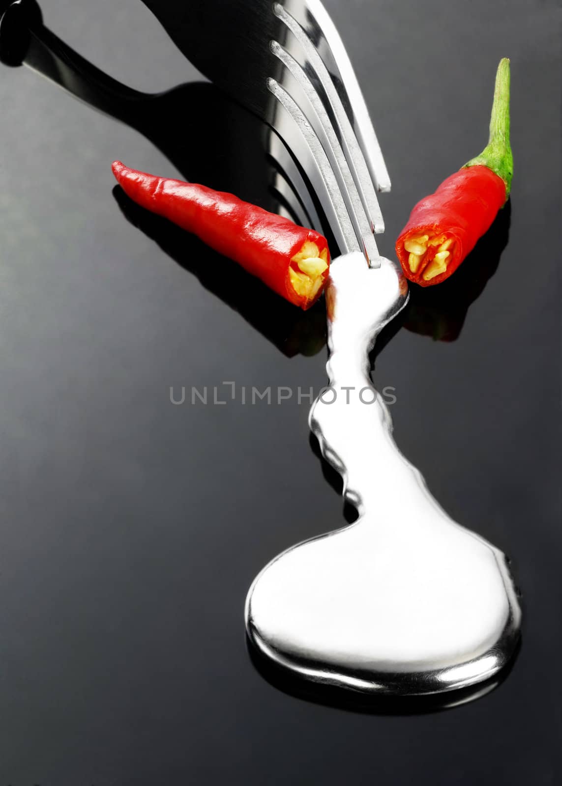 red chili pepper melting a fork while be cutted on a black stone