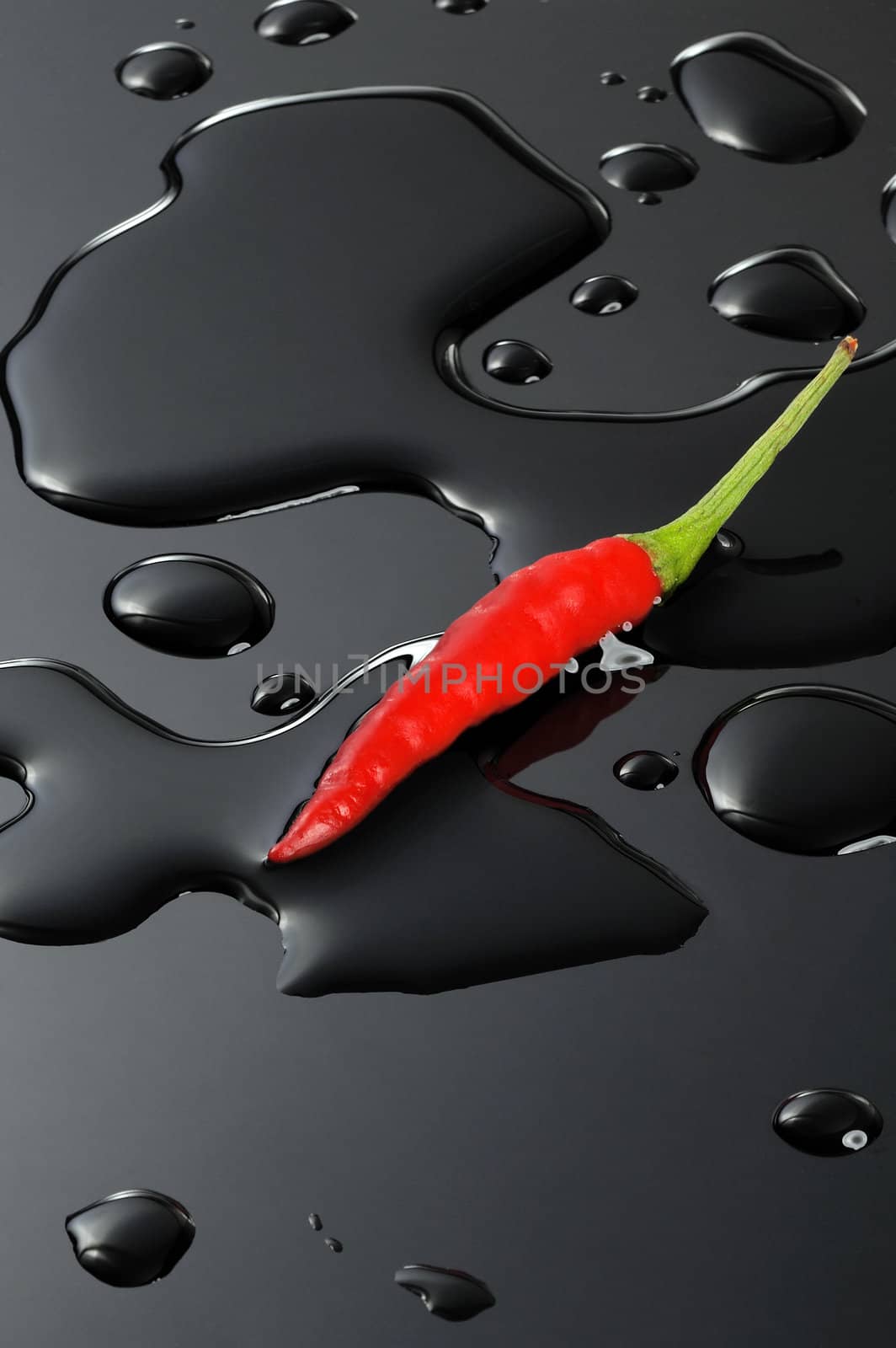 red chili pepper on water drops over a black stone