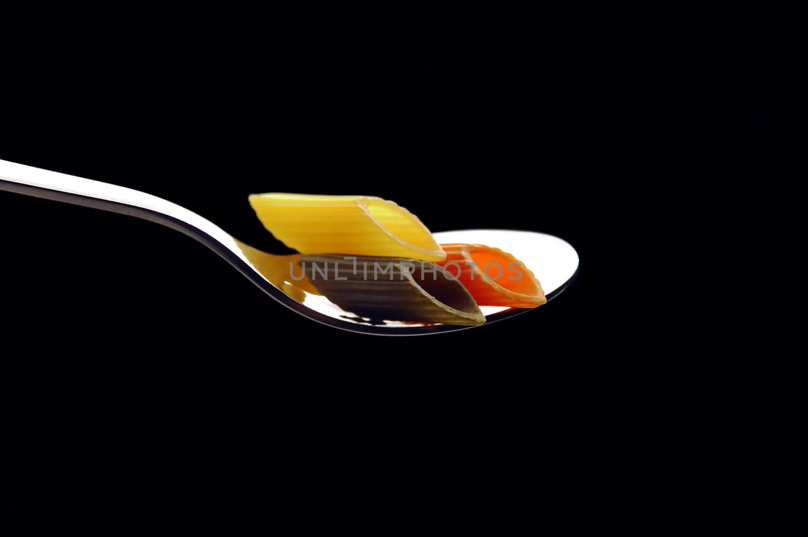 italian penne pasta on a spoon ,on black background