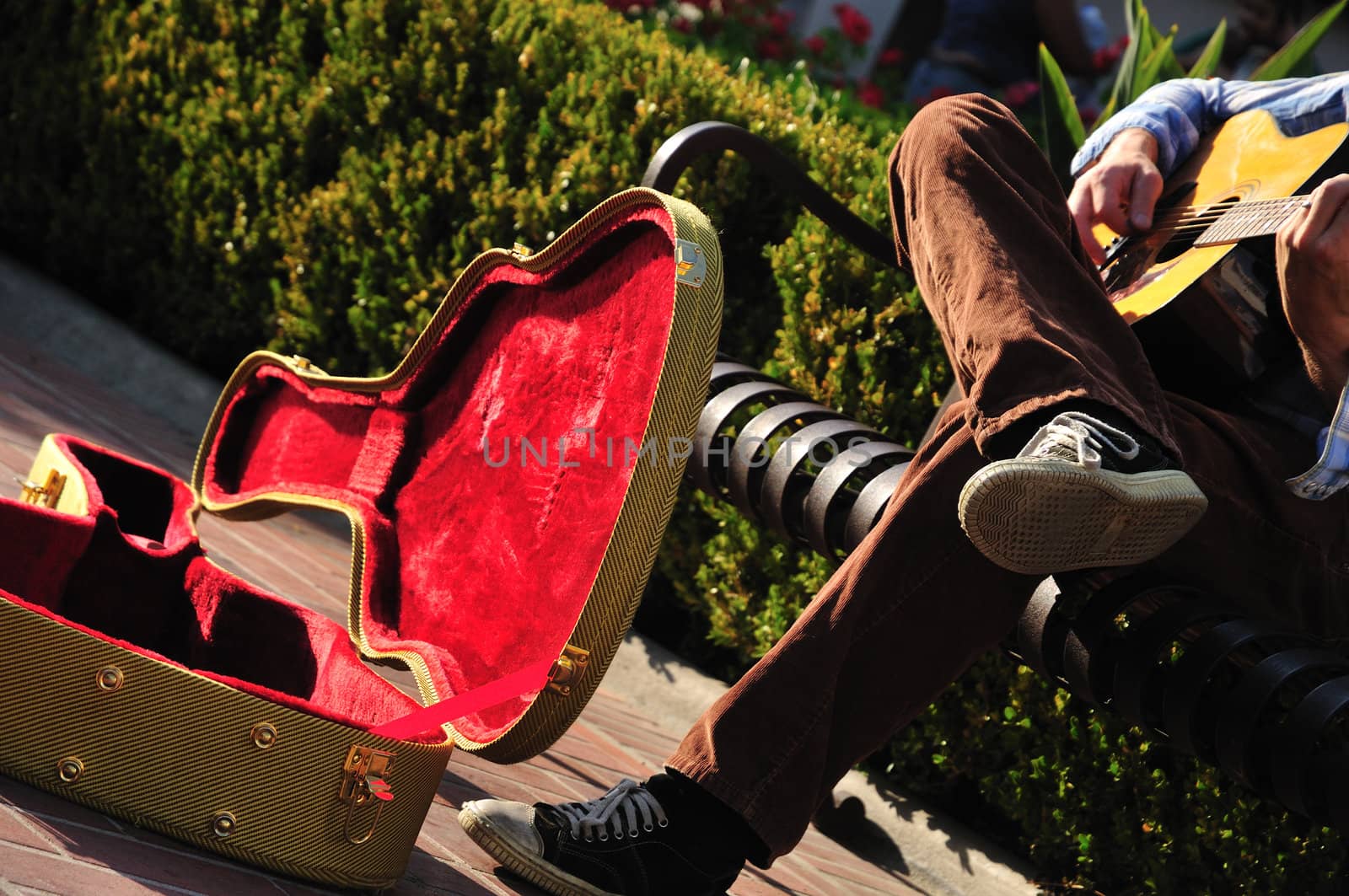 Red-lined guitar case of a street musician sitting on a bench