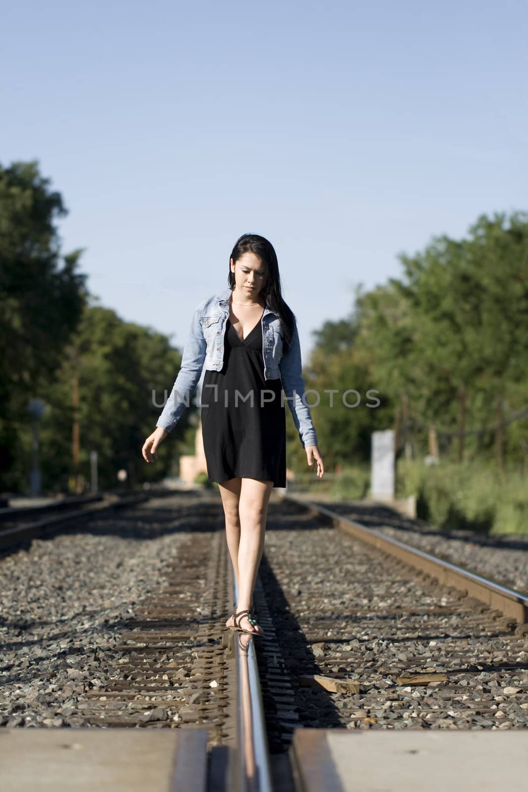 Pretty teen walking alone on train tracks on a beautiful day