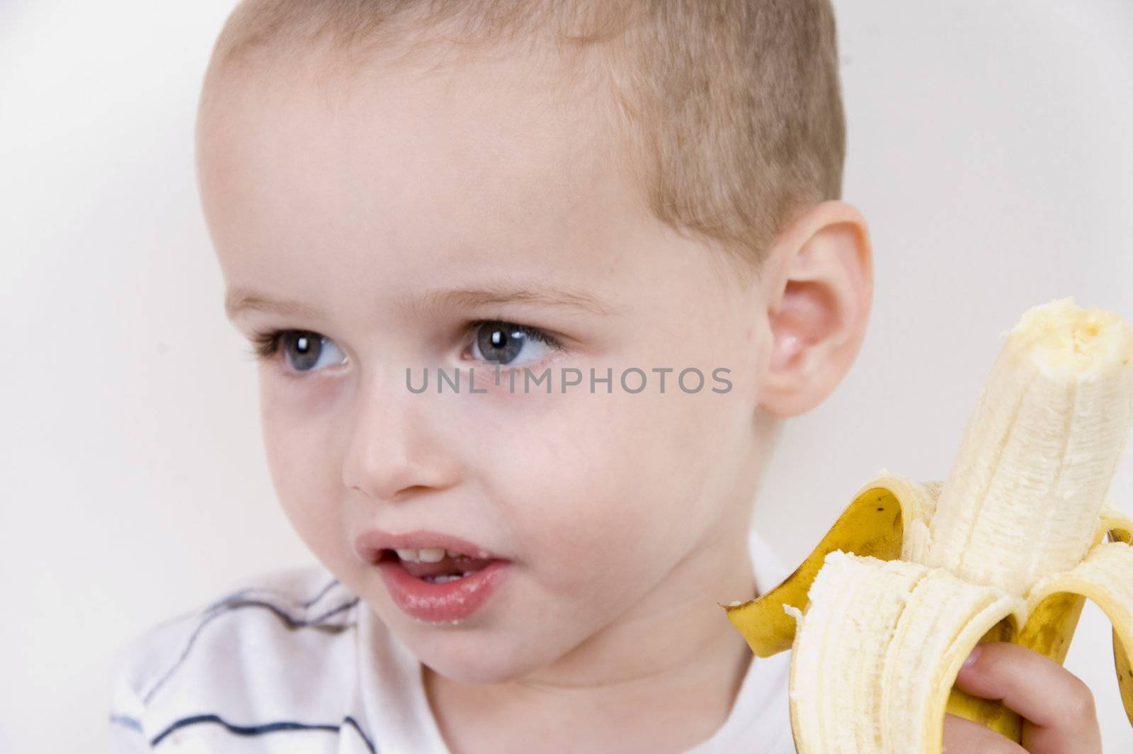 portrait of little boy with peeled banana