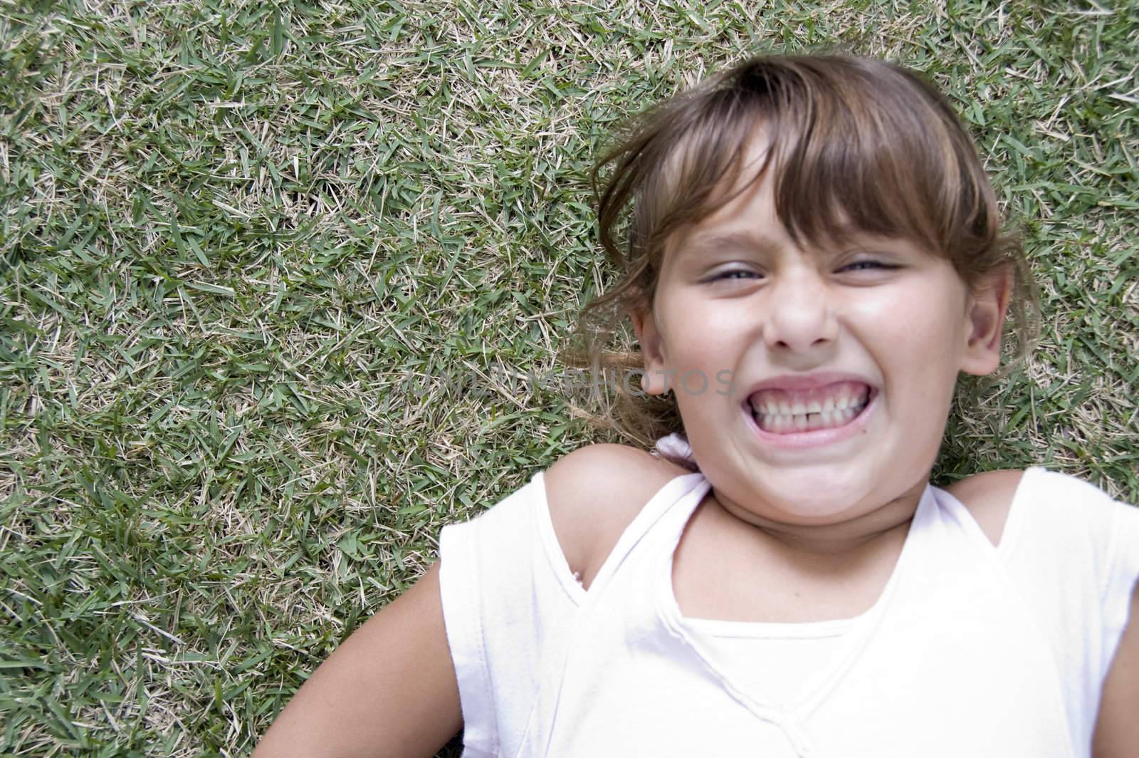 girl laying down on grass with clenched teeth