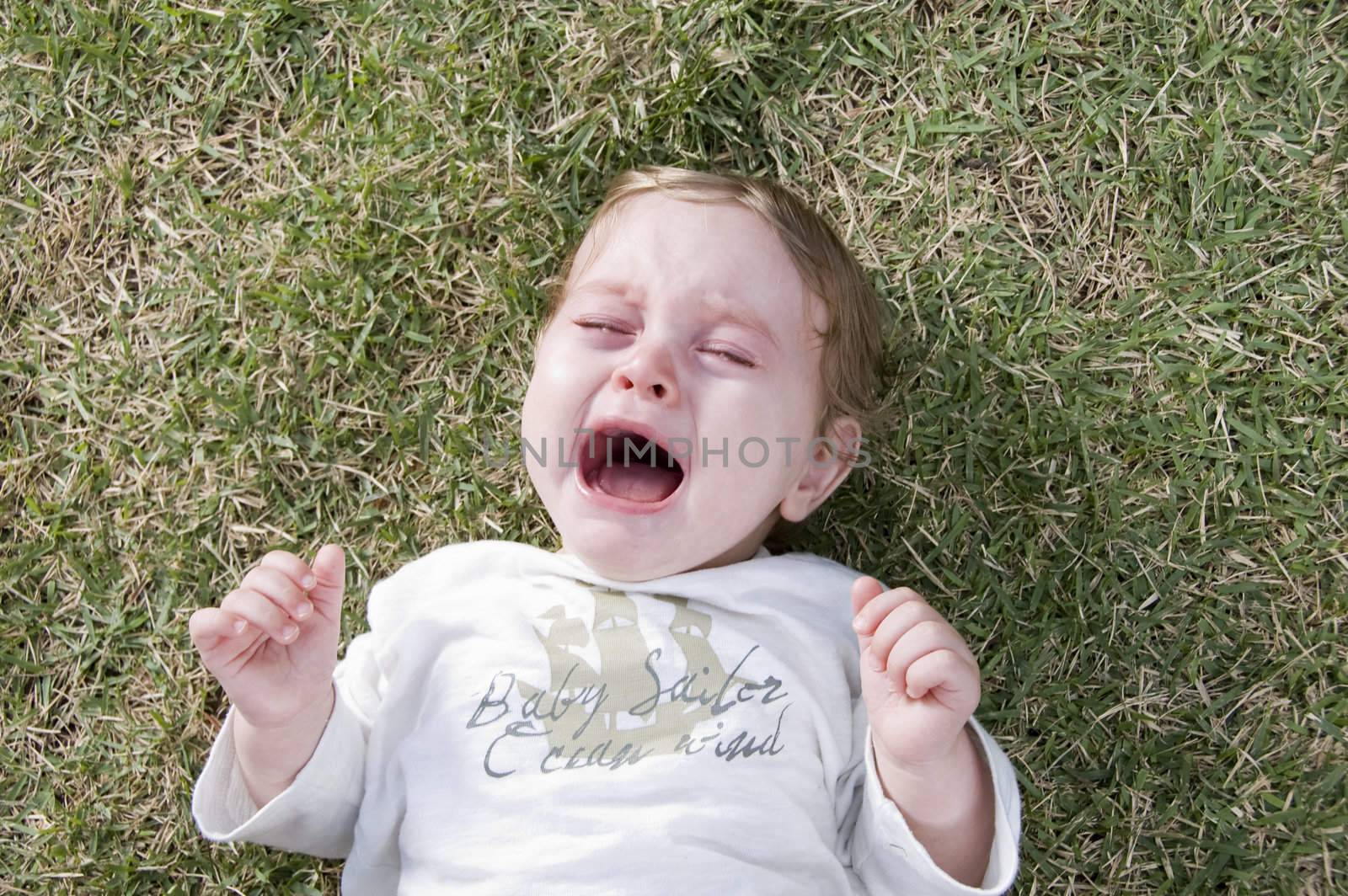 adorable child crying and lying in the garden
