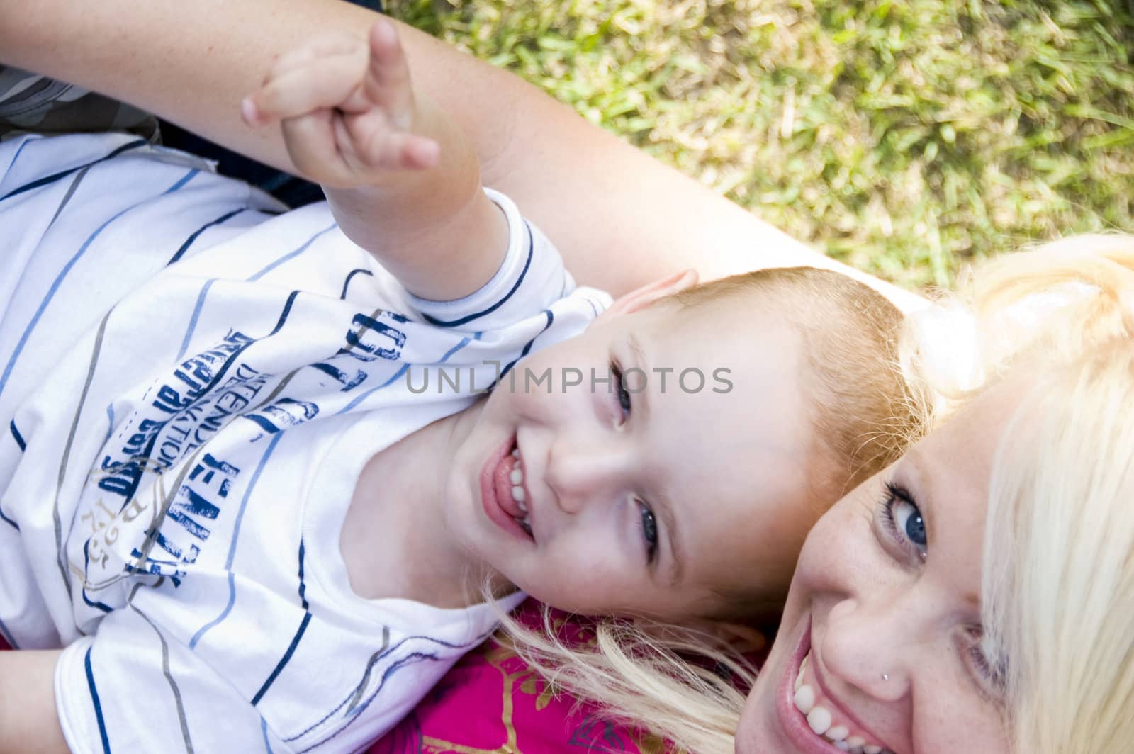 blonde young mother posing with her baby lying on grass