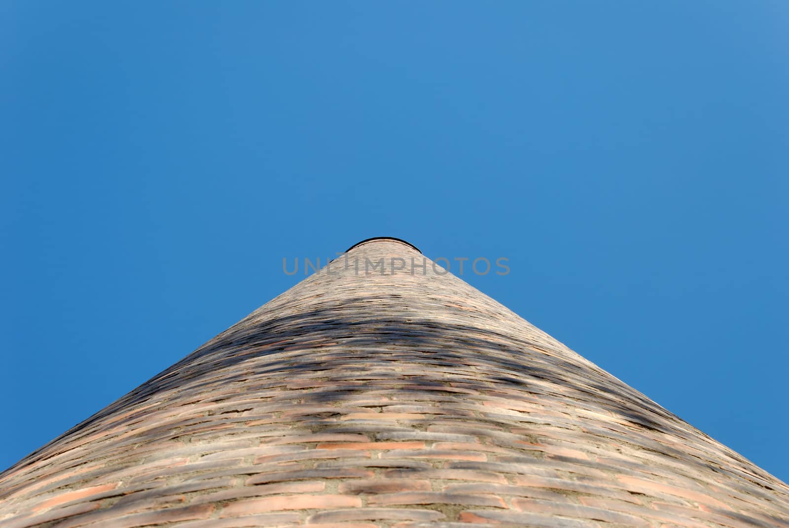 Brick factory chimney seen in perspective straight from below.
